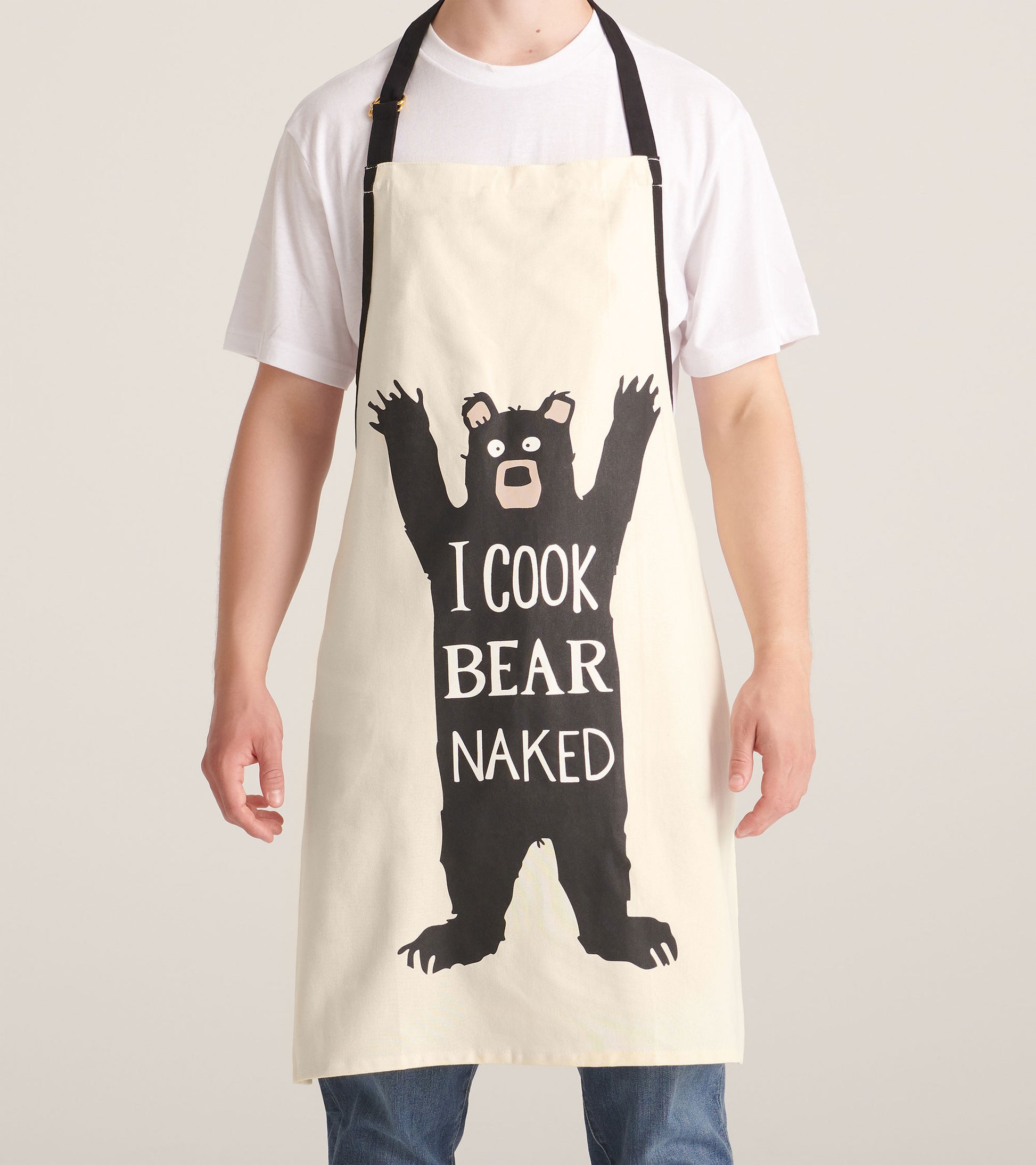Cream apron featuring a playful black bear graphic with the text "I COOK BEAR NAKED," ideal for cooking or grilling.