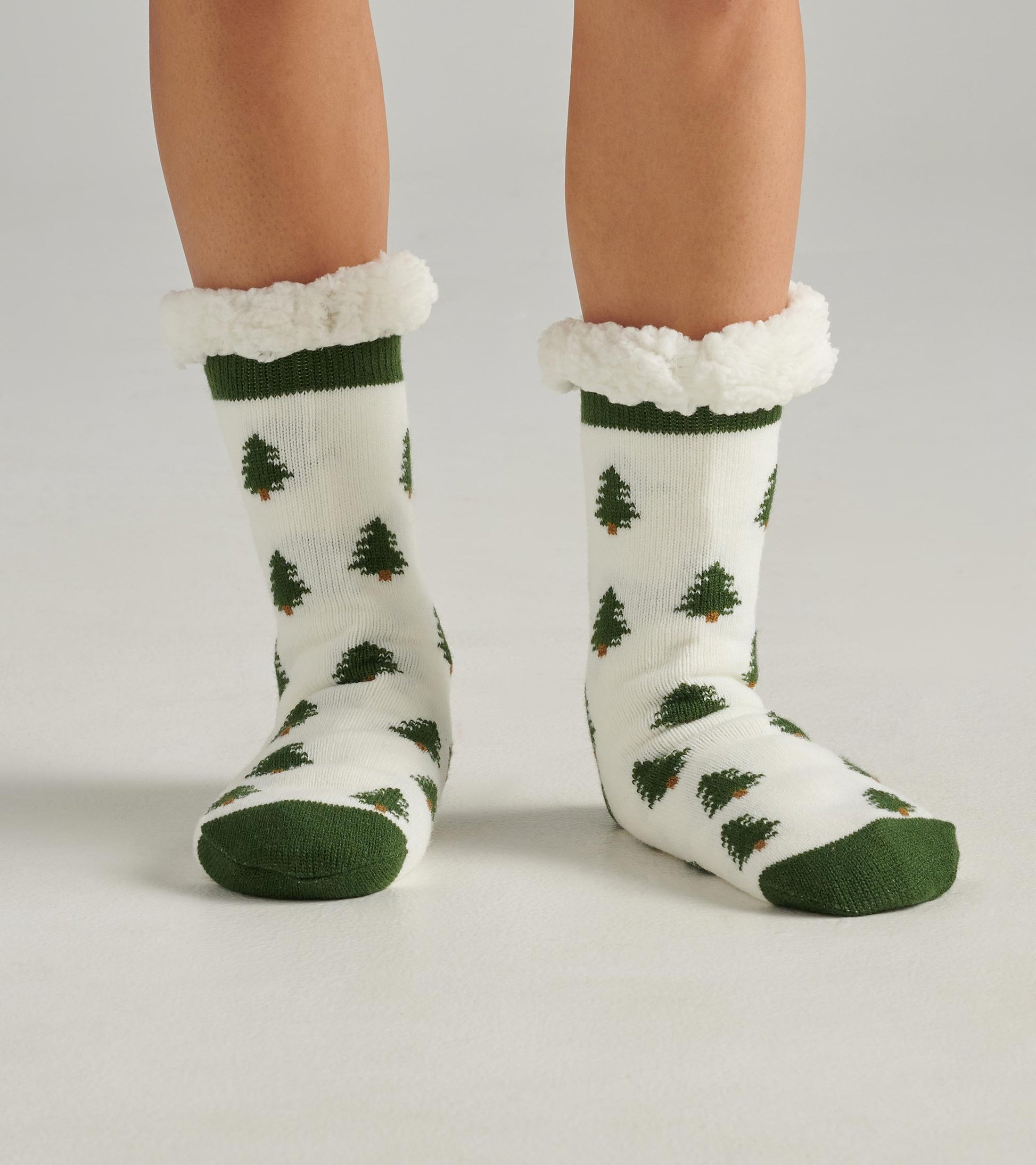 White socks with green tree patterns and a fluffy green cuff, designed for warmth and comfort. One size fits all.