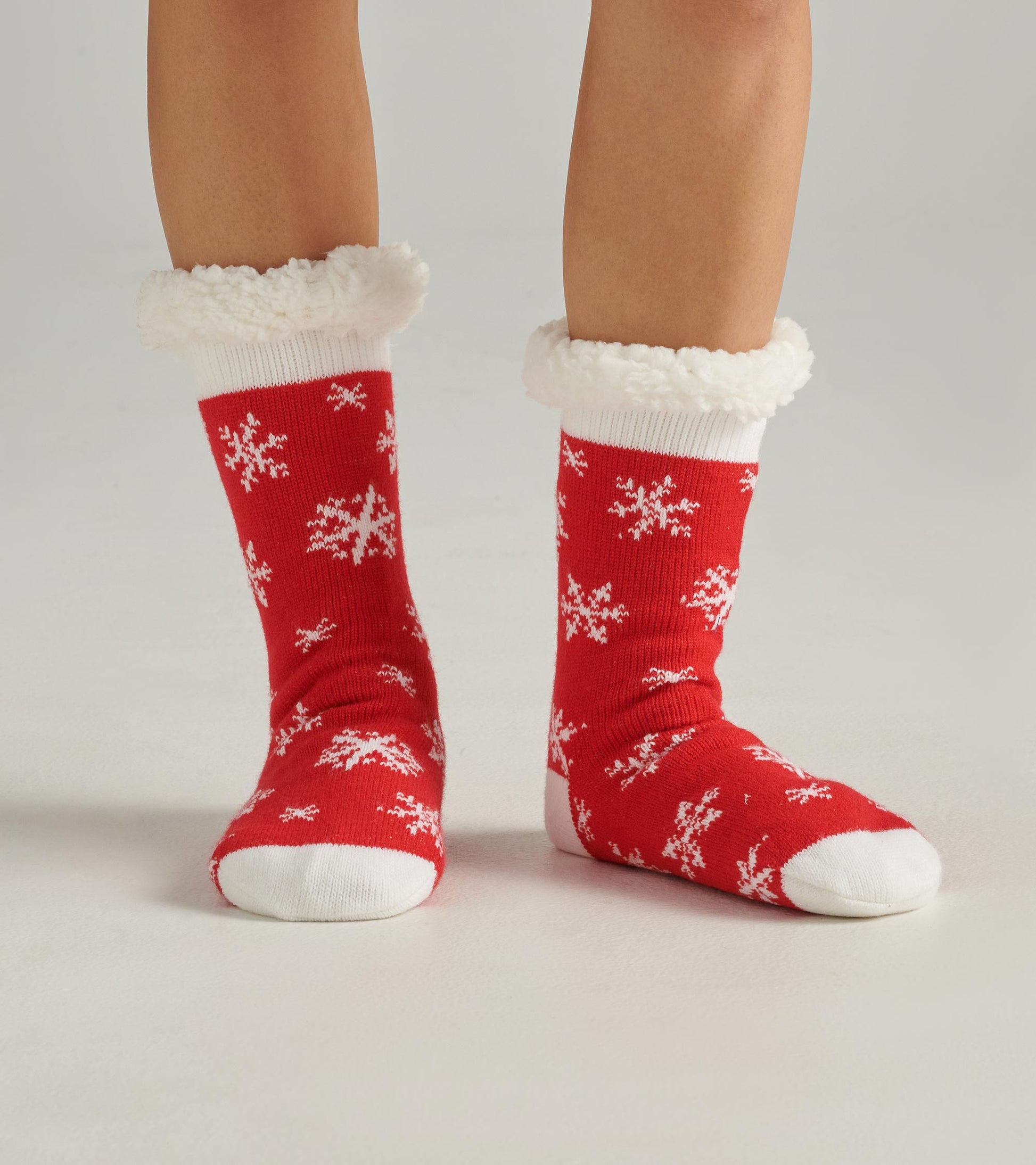 Red cabin socks with white snowflake pattern and fluffy white cuffs, designed for warmth and comfort.