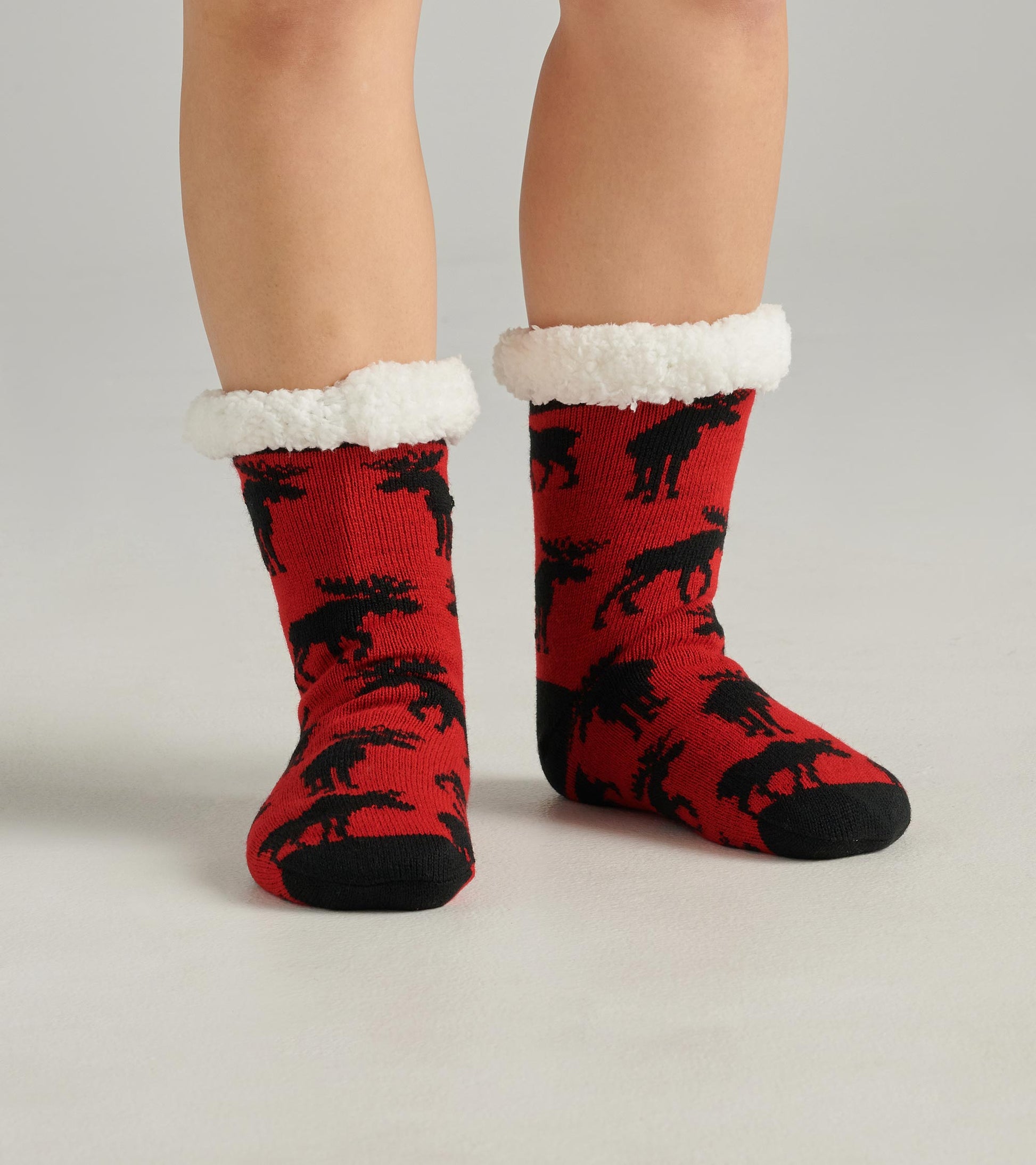 Red cabin socks with black moose pattern and white sherpa lining at the cuff, designed for warmth and comfort.