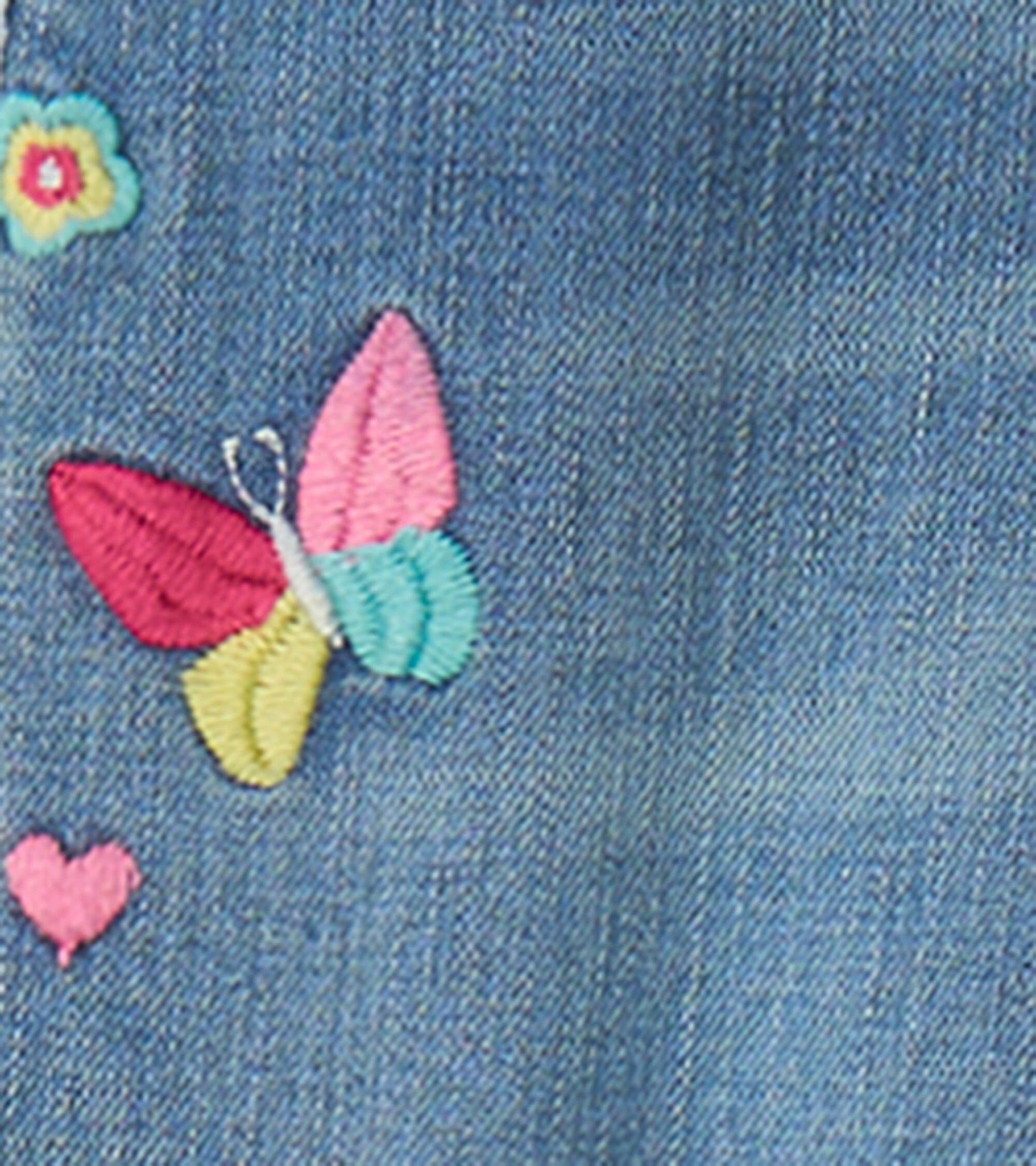 Light blue stretch jeans featuring colorful embroidered butterfly and flower patches.