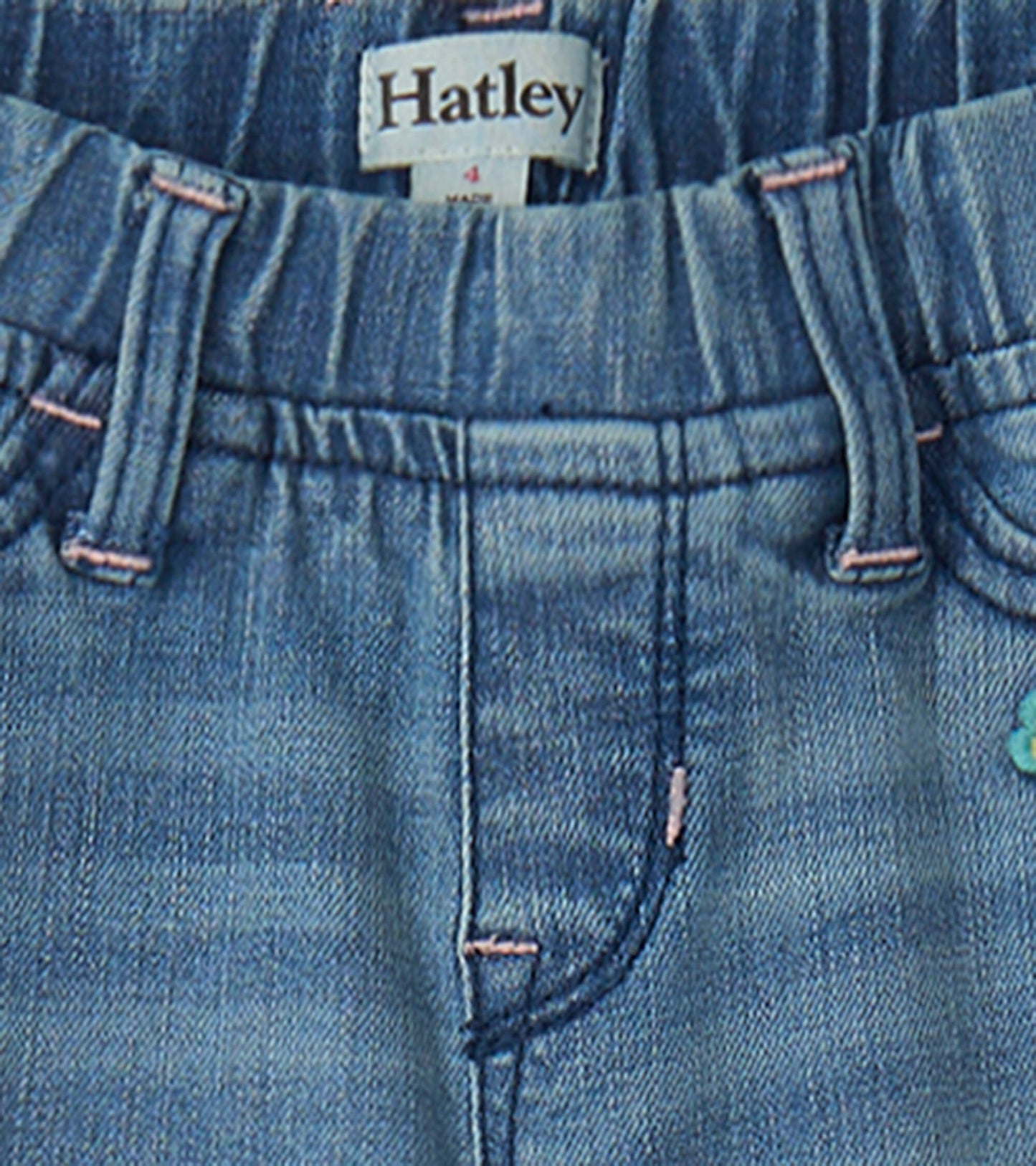Light blue stretch denim jeans with decorative patches and pink stitching, featuring an elastic waistband for comfort.