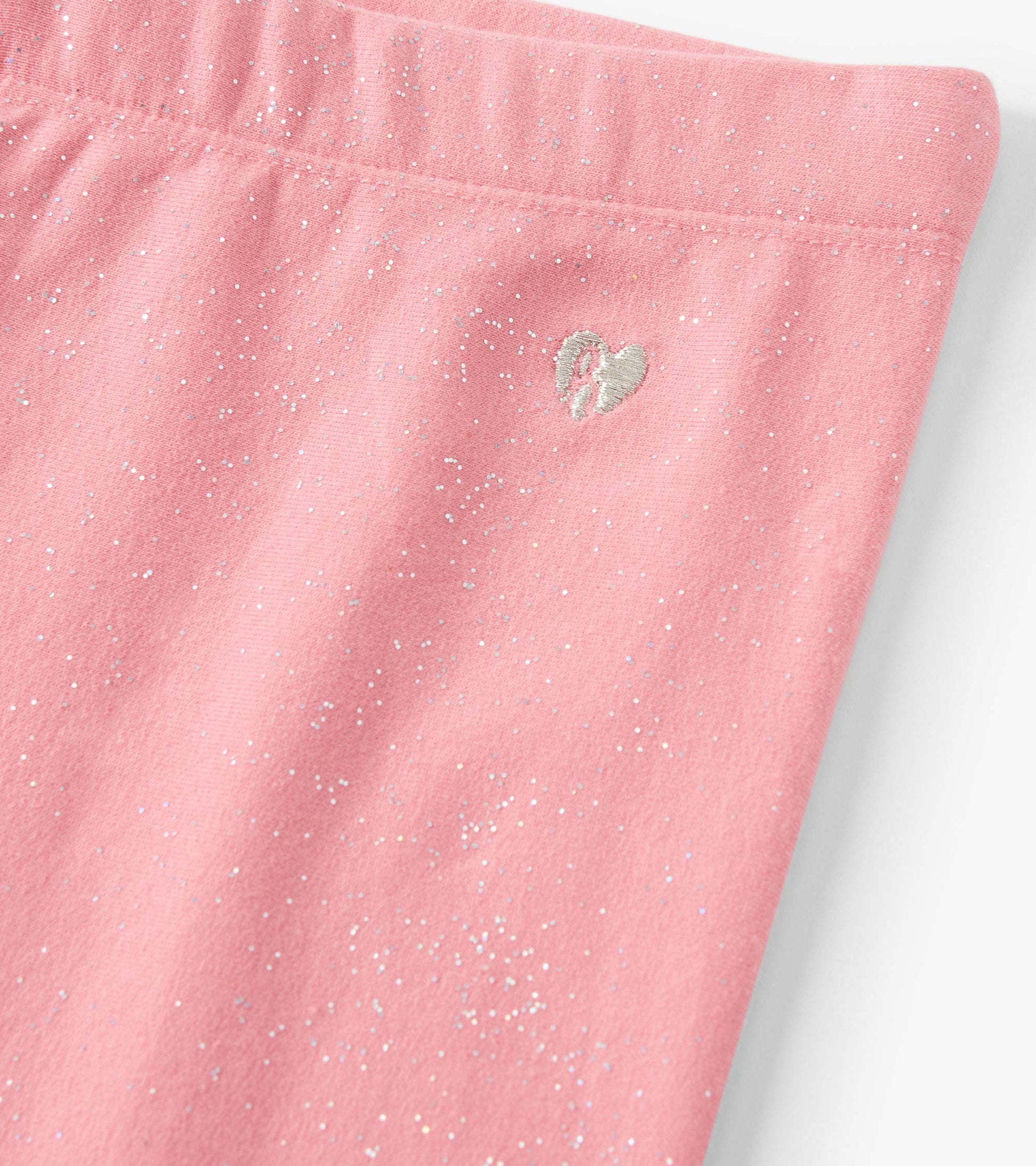Pink cozy leggings with a glittery finish and a small heart embroidery detail.