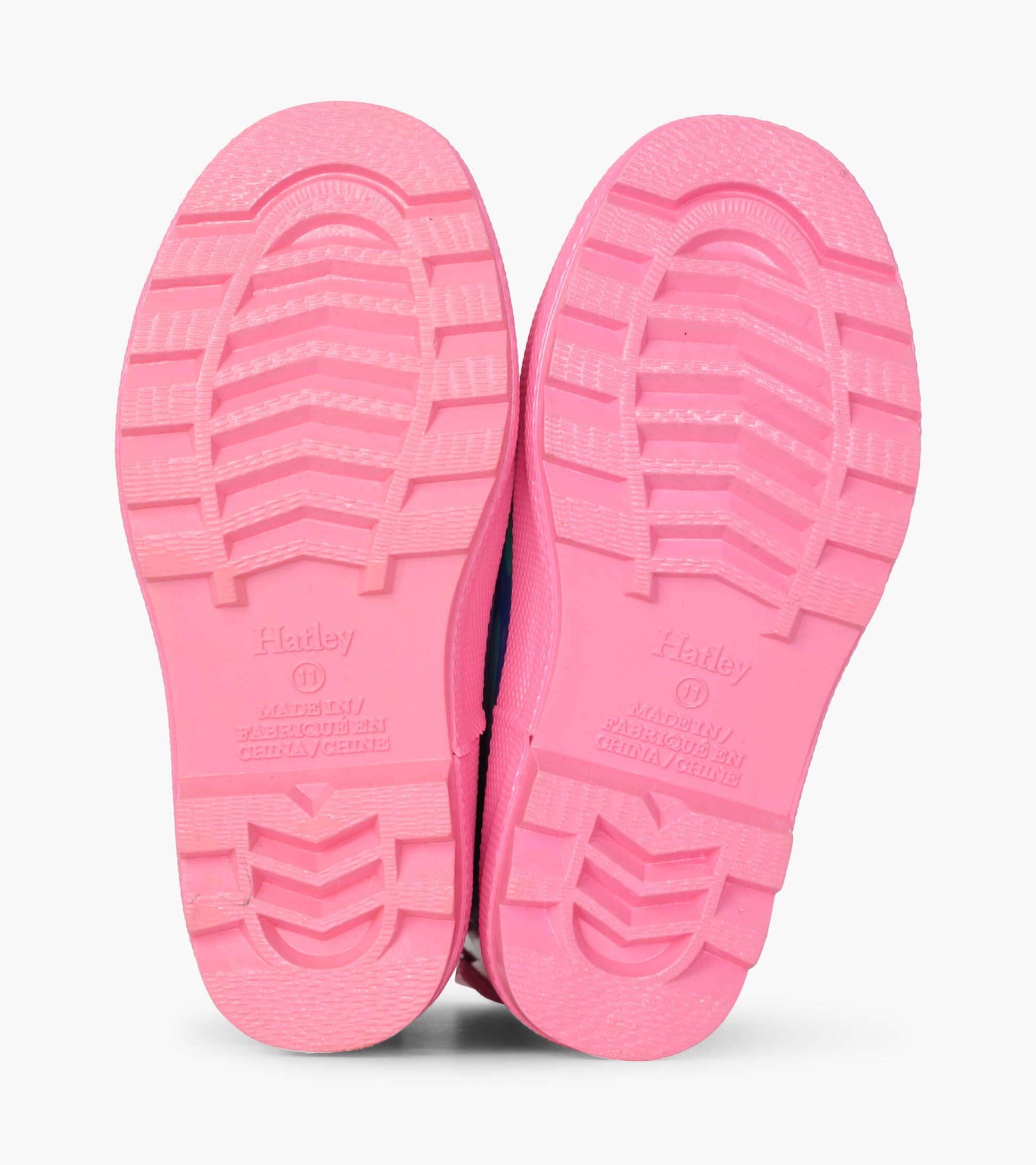 Pink rubber soles of rain boots with textured grip, designed for kids, showcasing a cheerful cloud pattern.