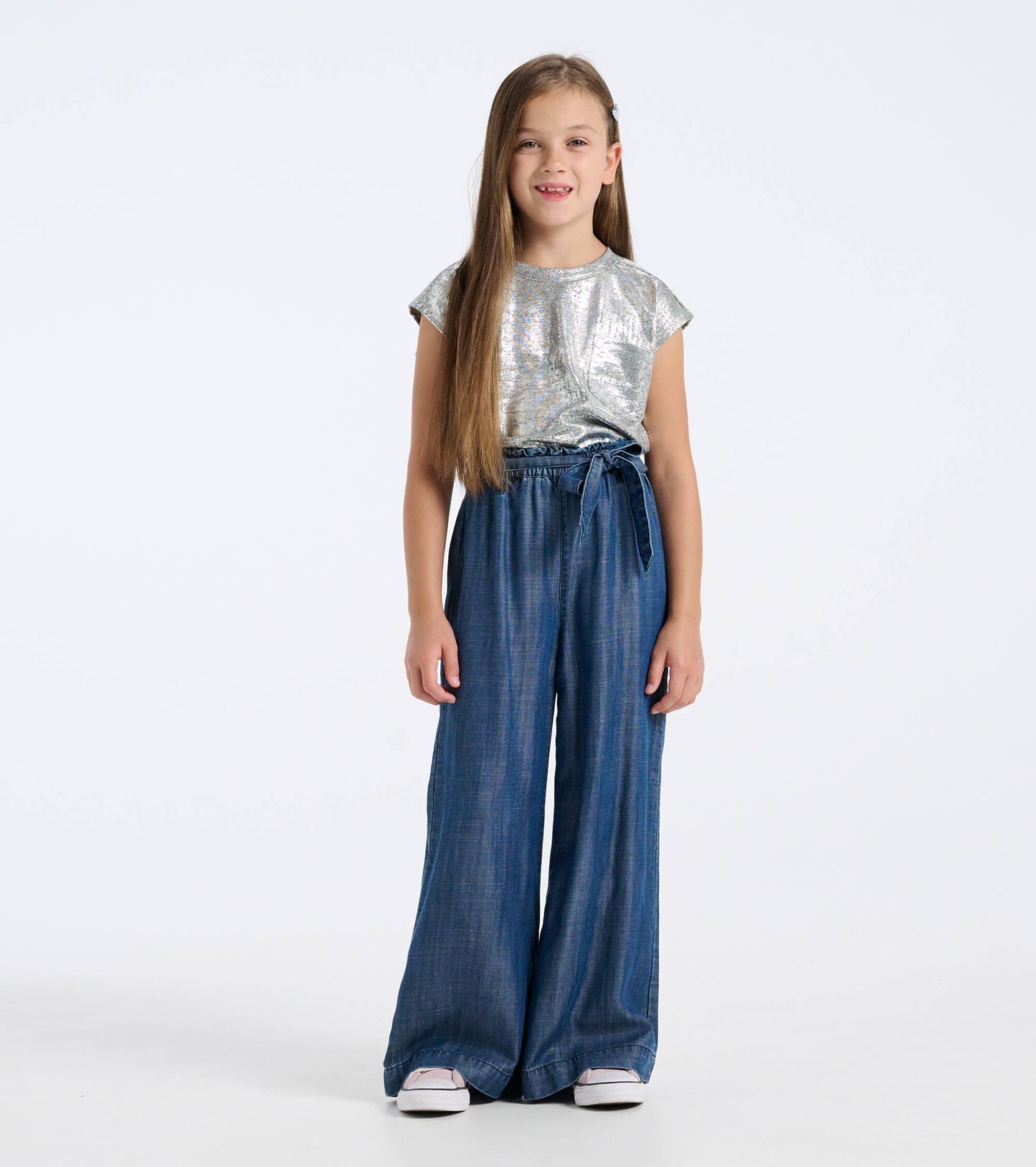 Blue textured paperbag pants with a wide leg and tie waist, worn by a girl with long hair and a silver top.