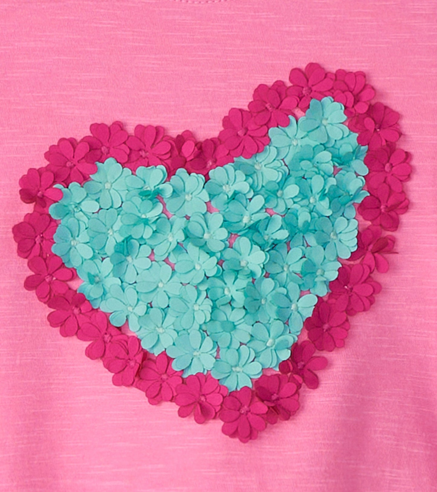 Pink long sleeve t-shirt featuring a heart design made of teal and magenta flower appliqués.