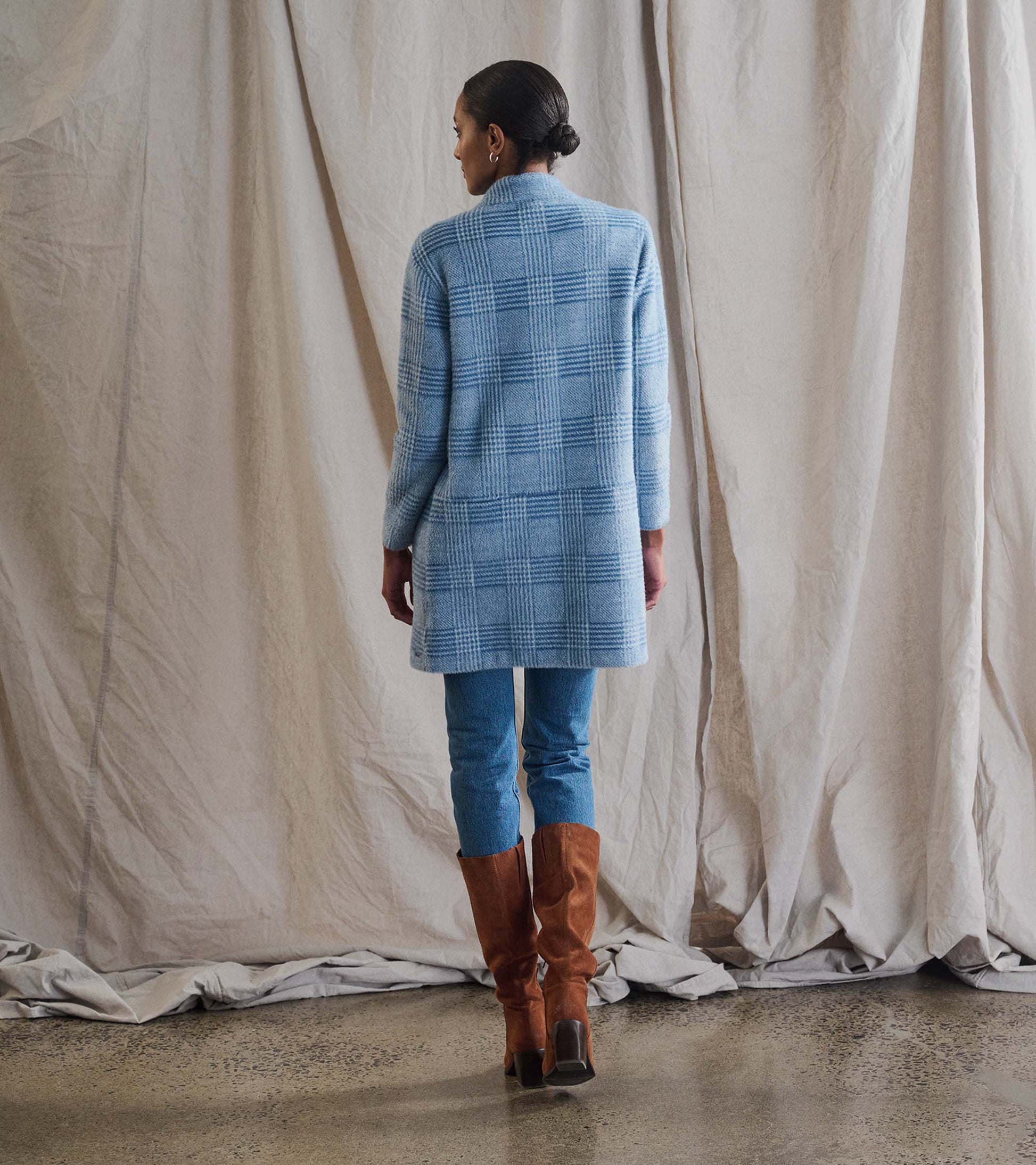 Open front jacket in blue check pattern, featuring long sleeves and a relaxed fit, styled with denim and knee-high boots.