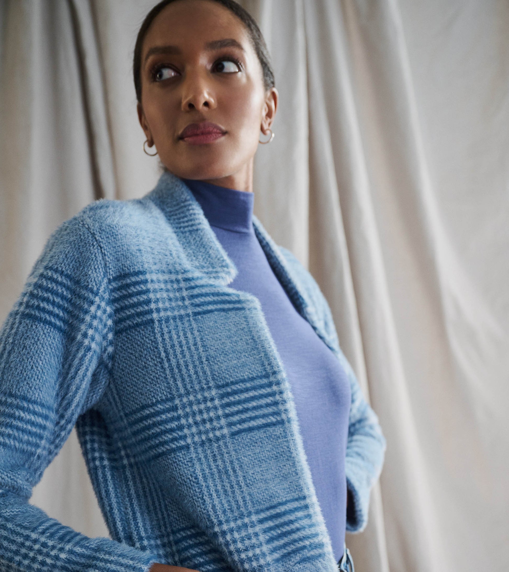 Open front jacket in a blue check pattern, featuring a soft texture and relaxed fit, styled over a purple top.