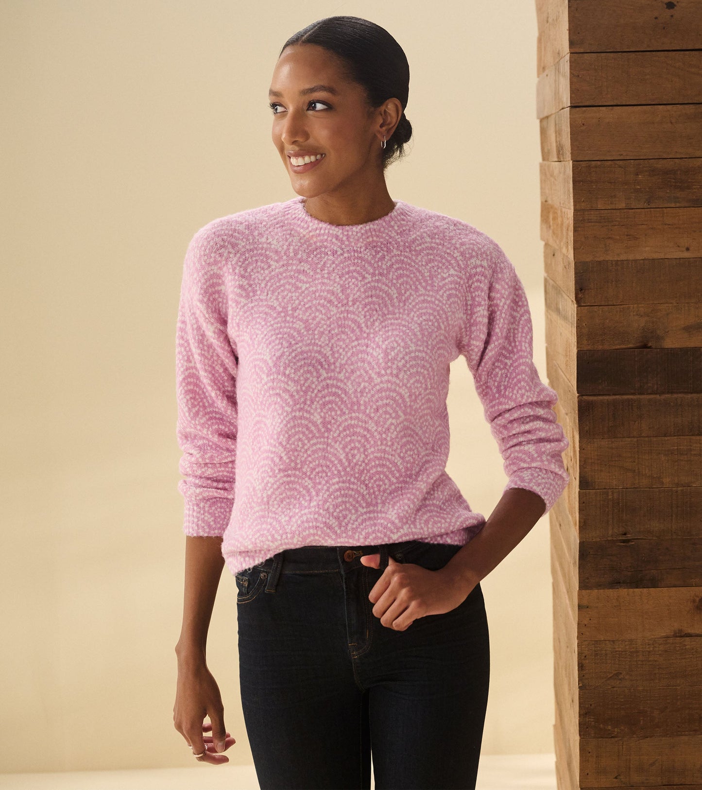 Light pink sweater with a decorative dot pattern, featuring long sleeves and a round neckline, styled with dark jeans.