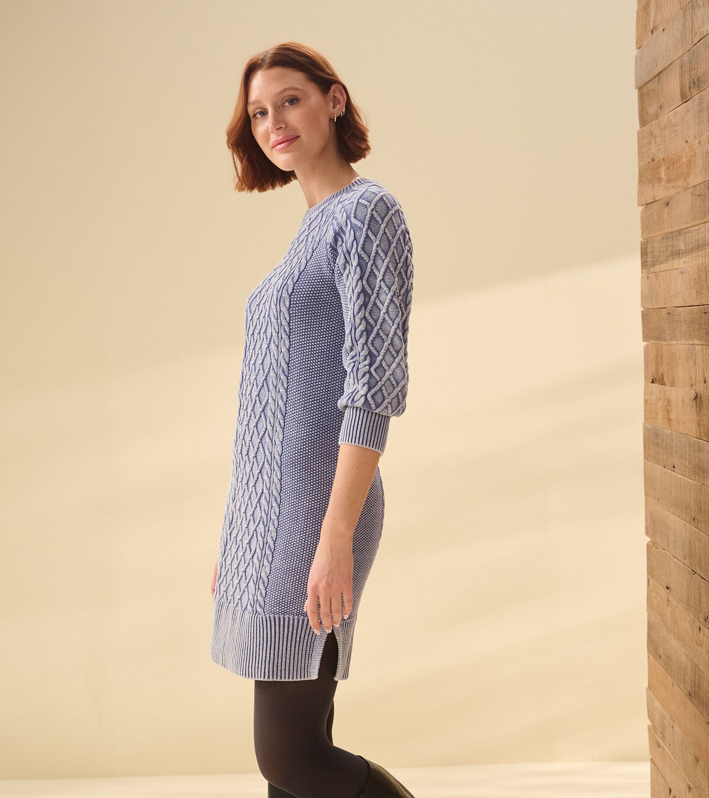 Cable knit dress in bleached denim with three-quarter sleeves and side slits, styled on a model against a neutral background.