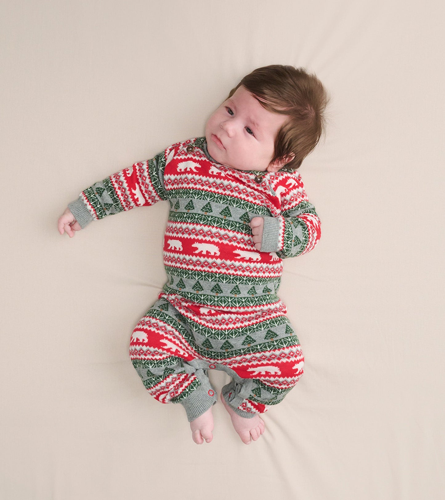 Red and gray Fair Isle sweater romper with polar bear and tree patterns, designed for infants, shown on a light background.