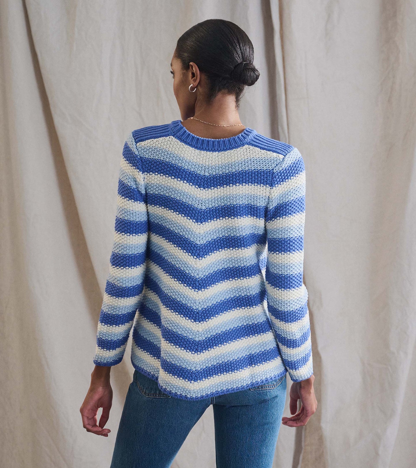 Navy blue chevron striped sweater with long sleeves and a round neckline, shown from the back.