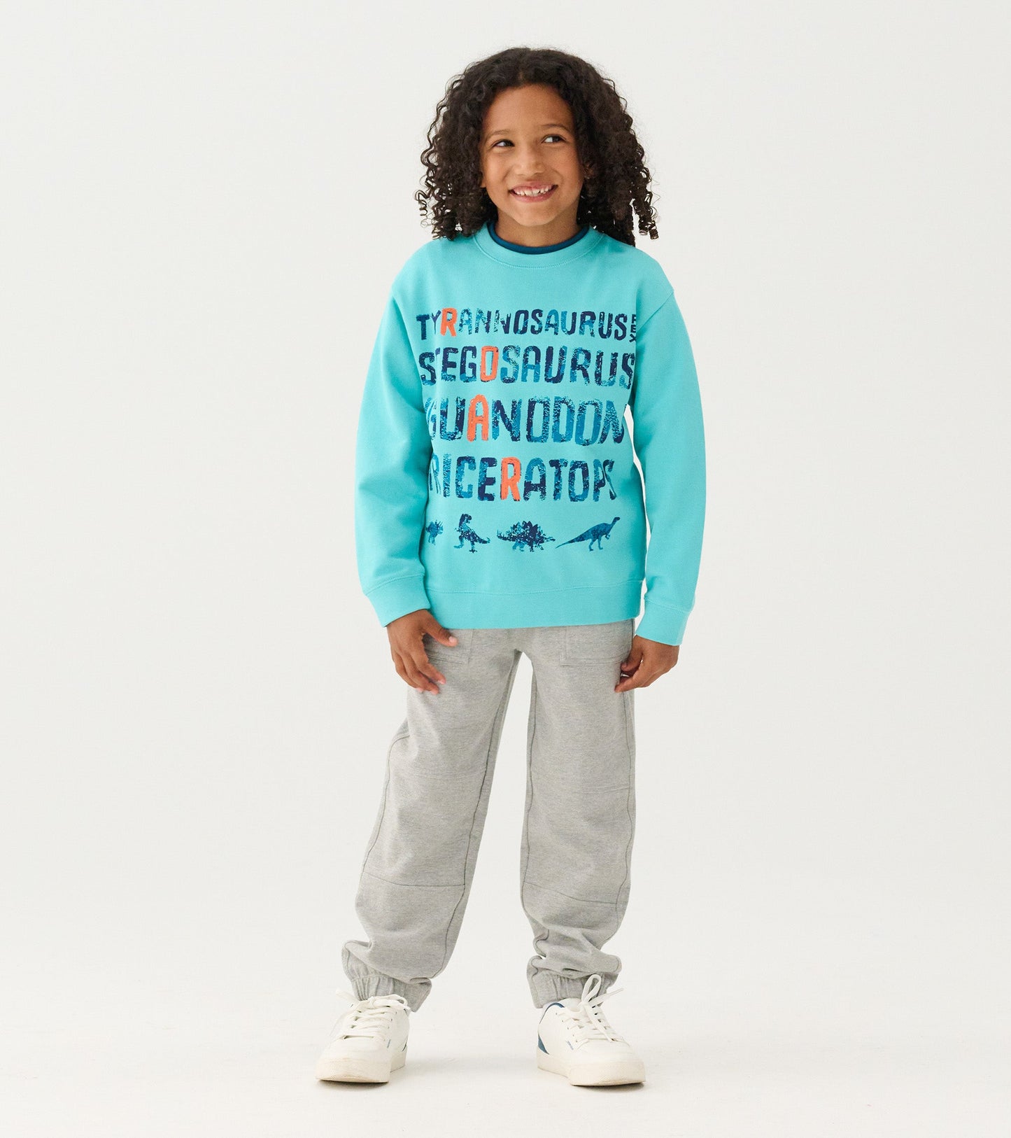 Turquoise sweatshirt featuring dinosaur names in colorful text, paired with gray sweatpants.