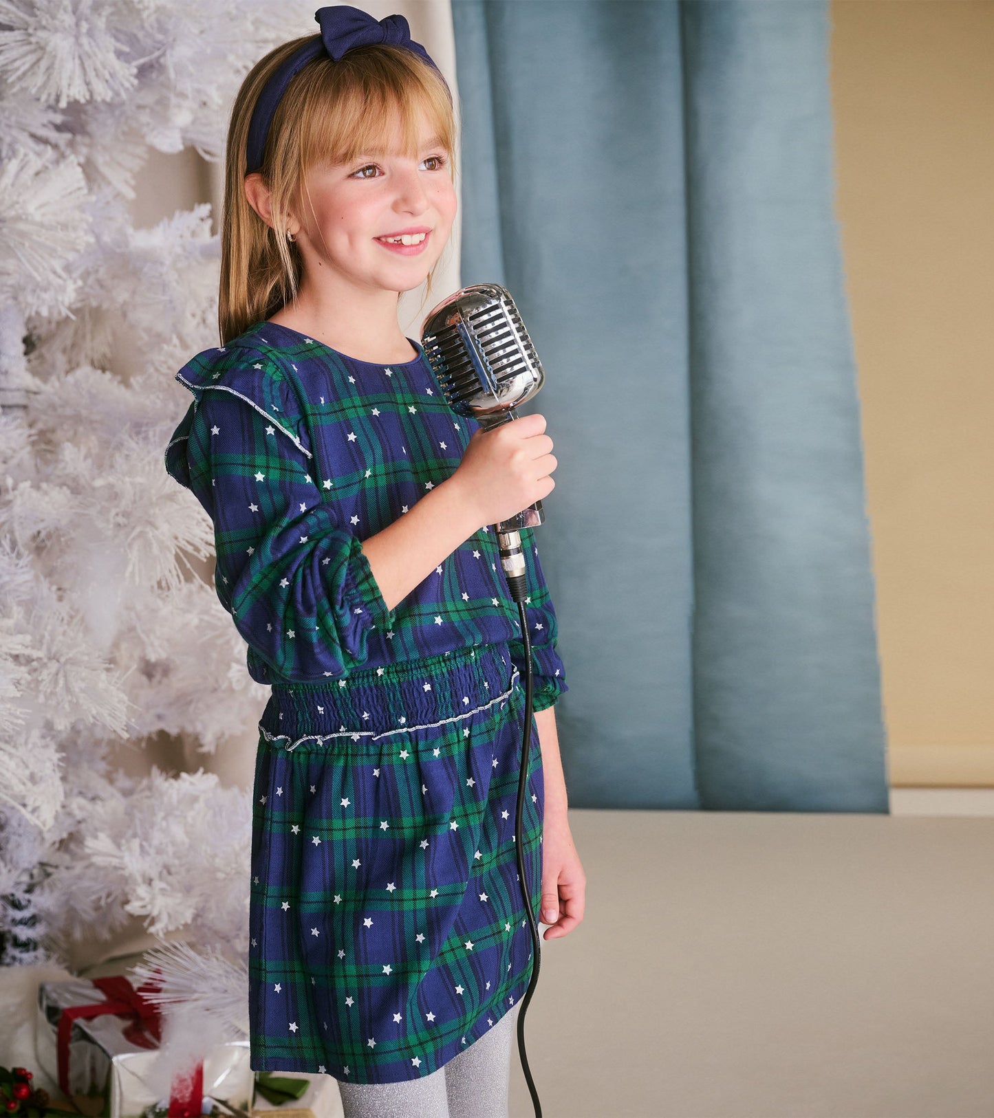 Girls' blackwatch plaid dress with smocked waist, featuring long sleeves and a playful star pattern.