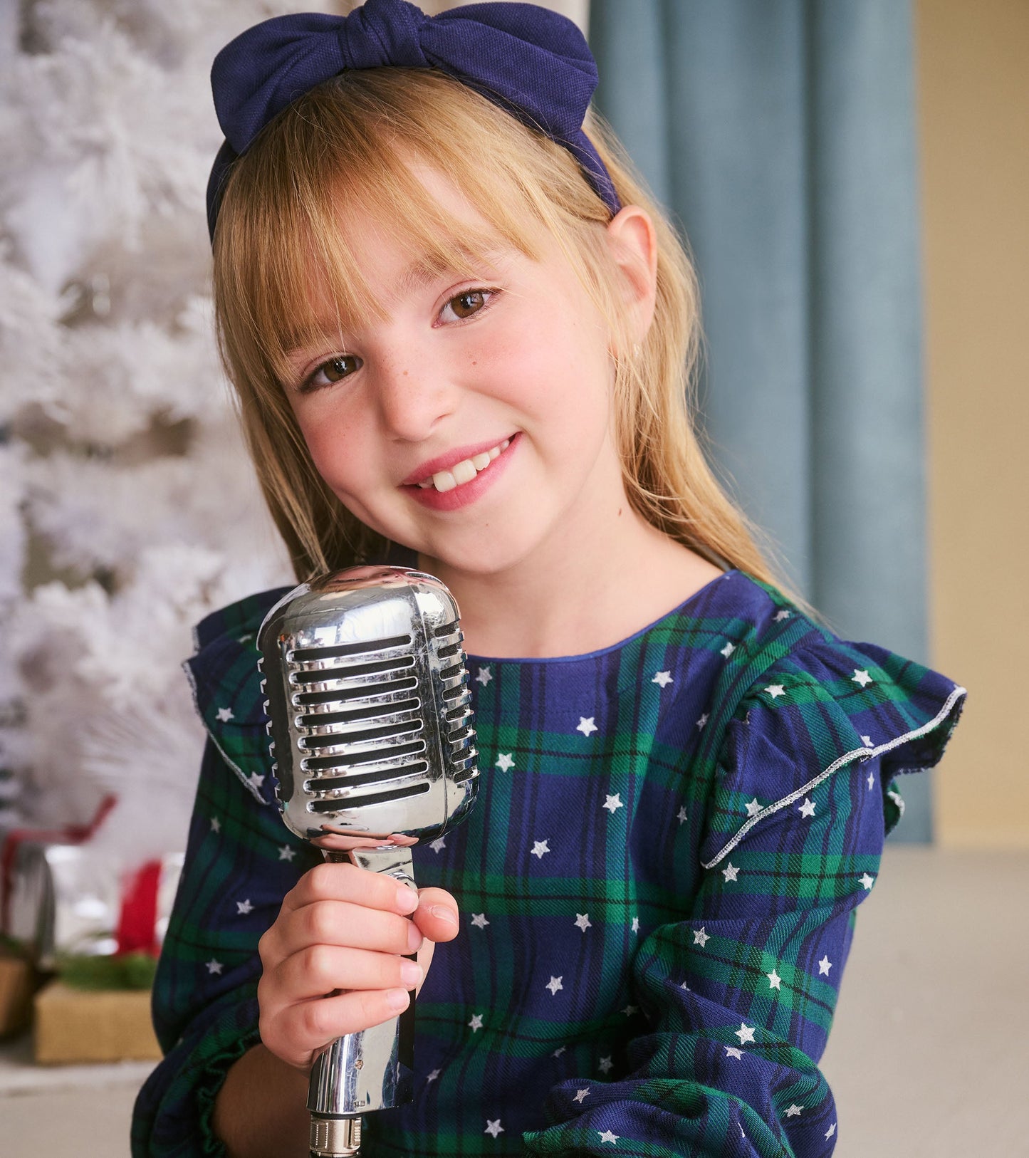 Girls' blackwatch plaid dress with smocked waist and ruffled sleeves, featuring a star pattern, worn by a smiling child.