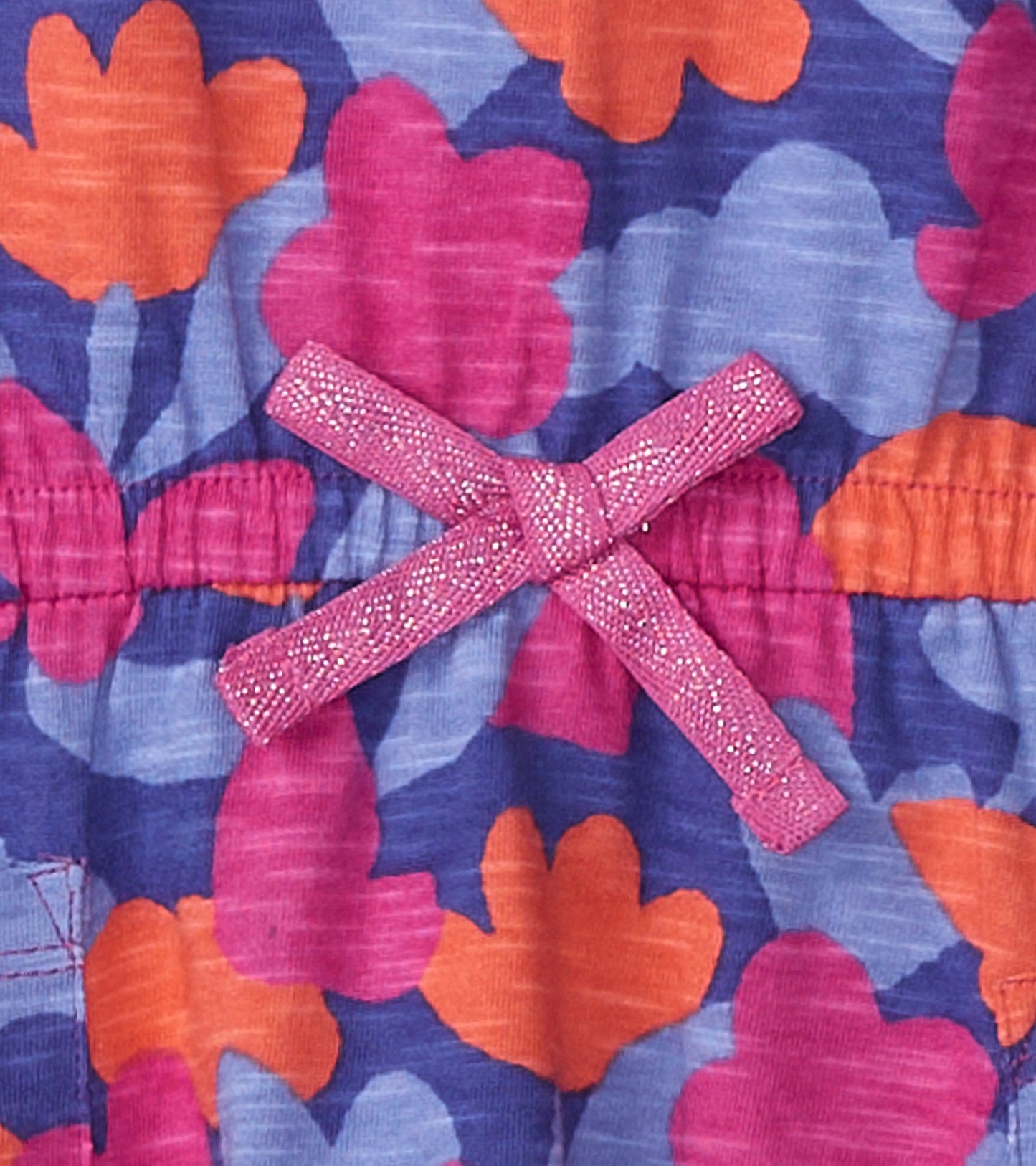 Colorful floral pattern in pink, orange, and blue with a sparkly pink bow at the waist on a drop waist t-shirt dress.
