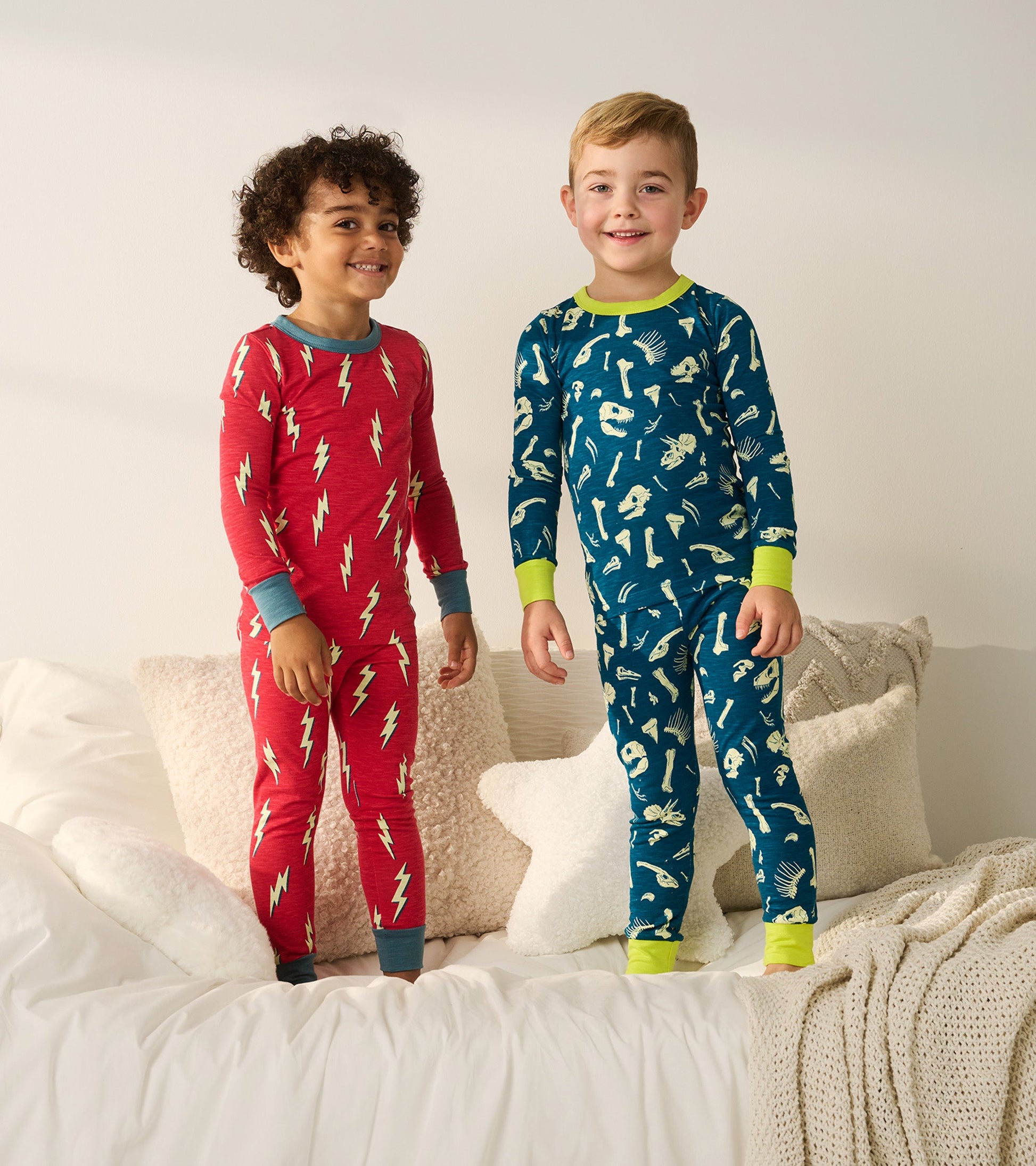 Red pajama set with lightning bolt pattern and blue accents, paired with blue pajama set featuring playful bone designs.