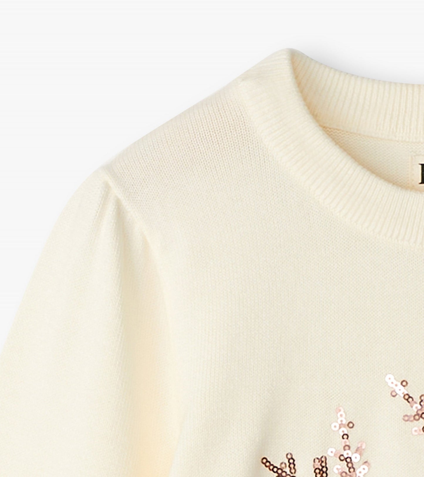 Cream pullover sweater featuring a snowflake design with sequins, round neckline, and puffed sleeves.