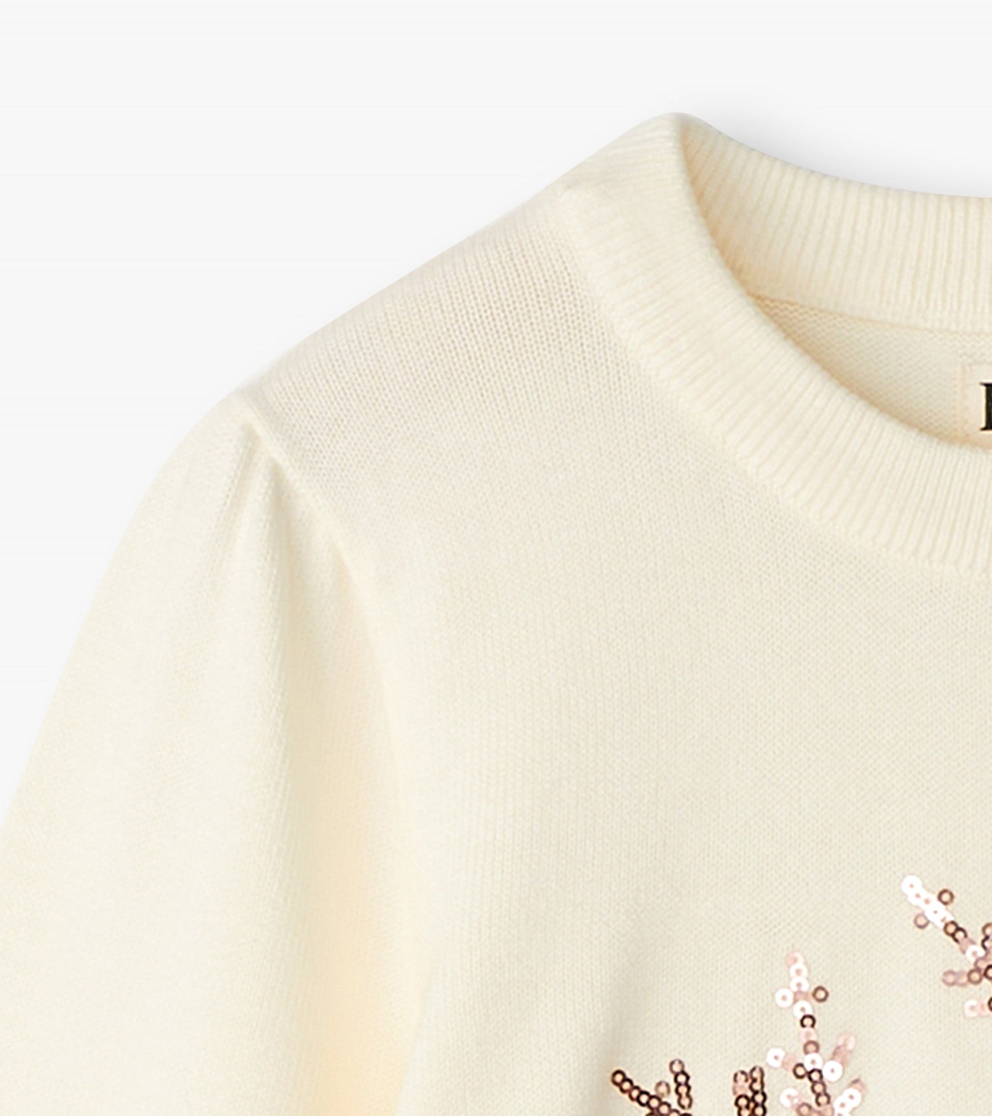 Cream pullover sweater featuring a snowflake design with sequins, round neckline, and puffed sleeves.