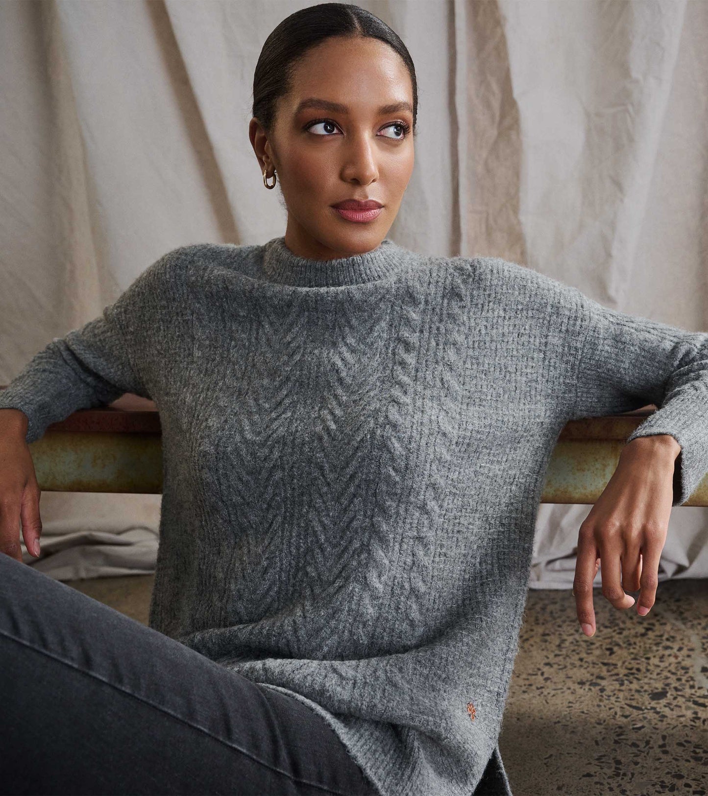 Charcoal heather cable knit tunic with a relaxed fit and high neckline, styled with dark jeans.