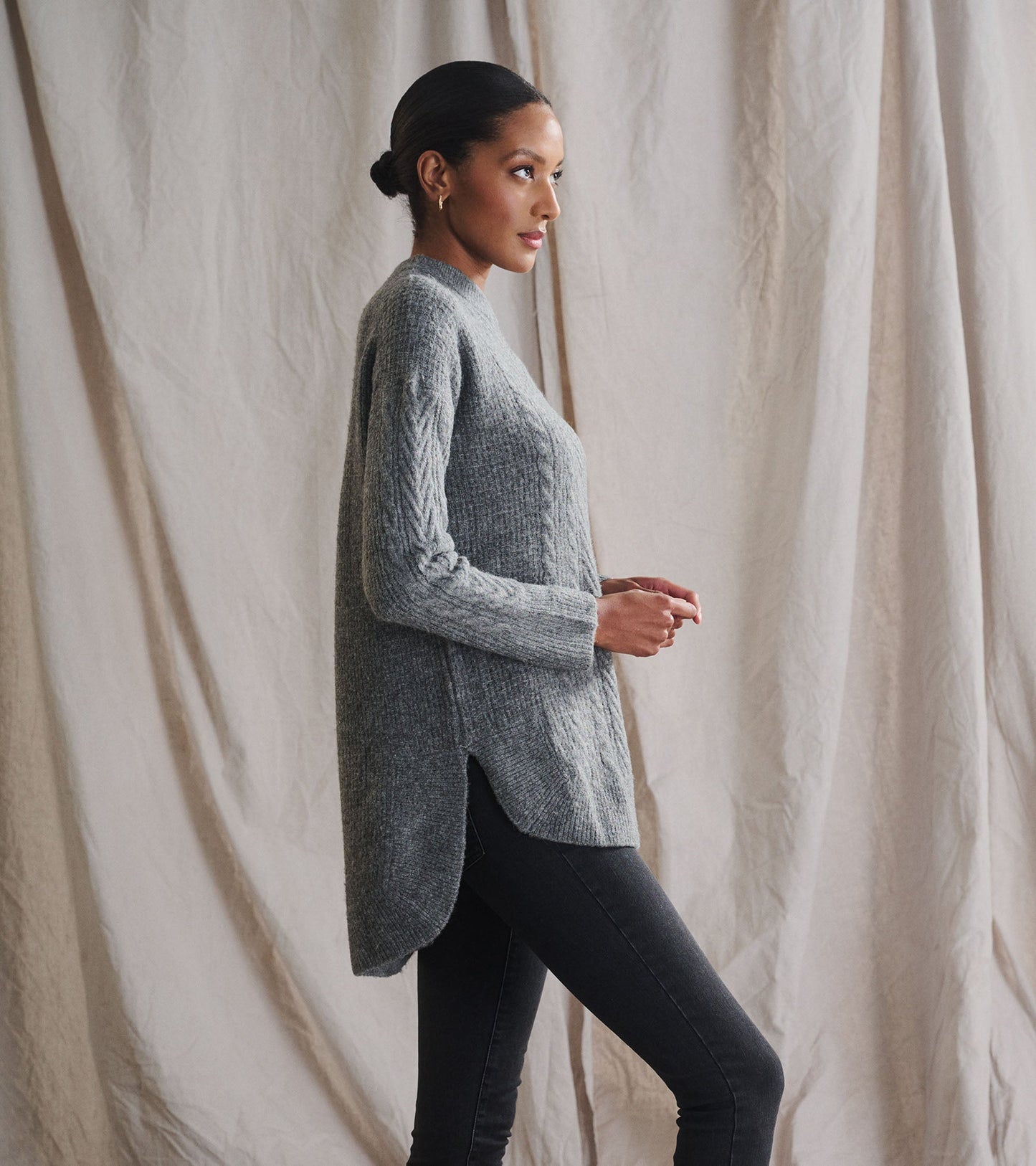 Charcoal heather cable knit tunic with a relaxed fit and side slits, styled with dark jeans.