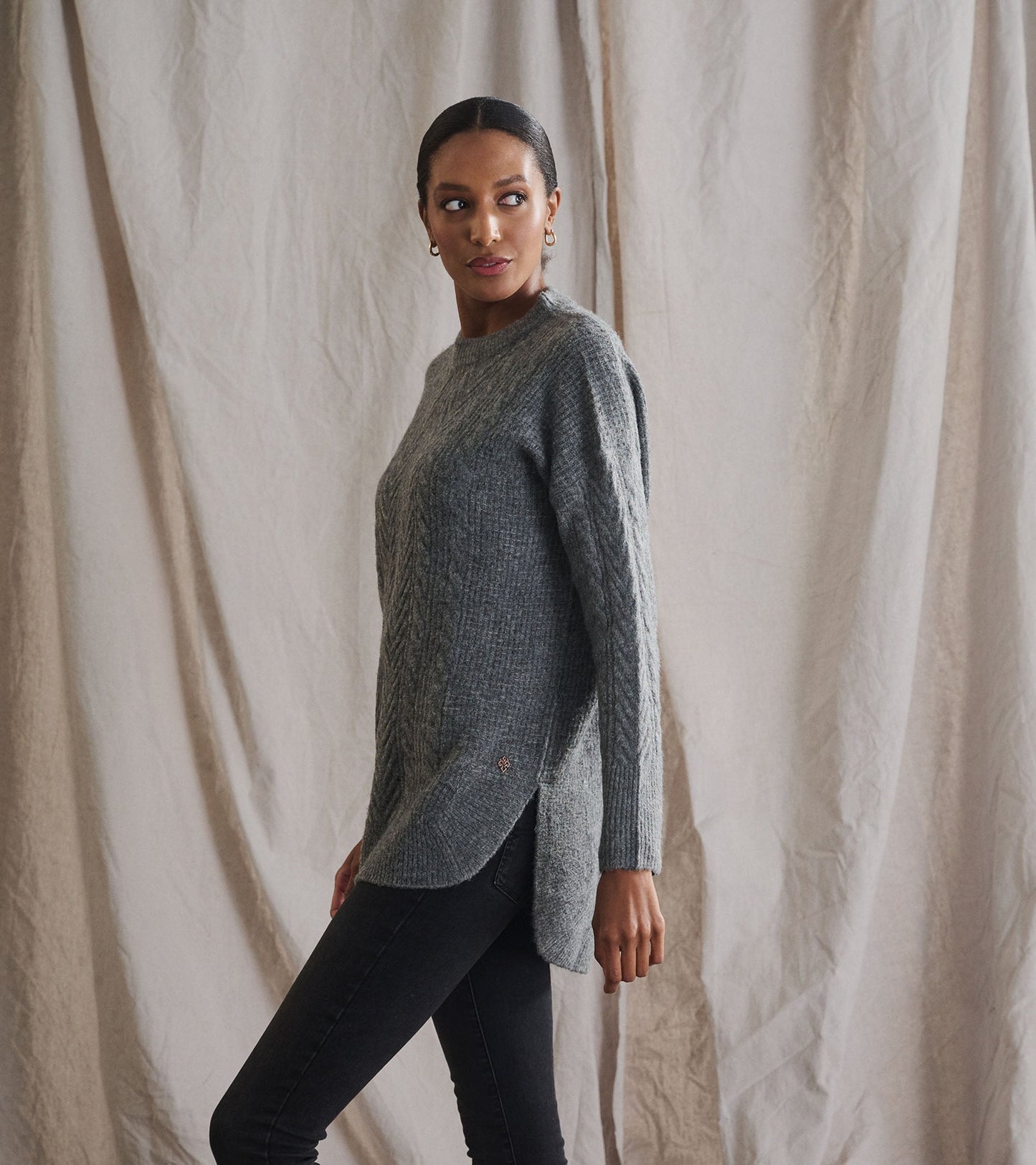 Charcoal heather cable knit tunic with a relaxed fit and side slits, styled with black jeans.