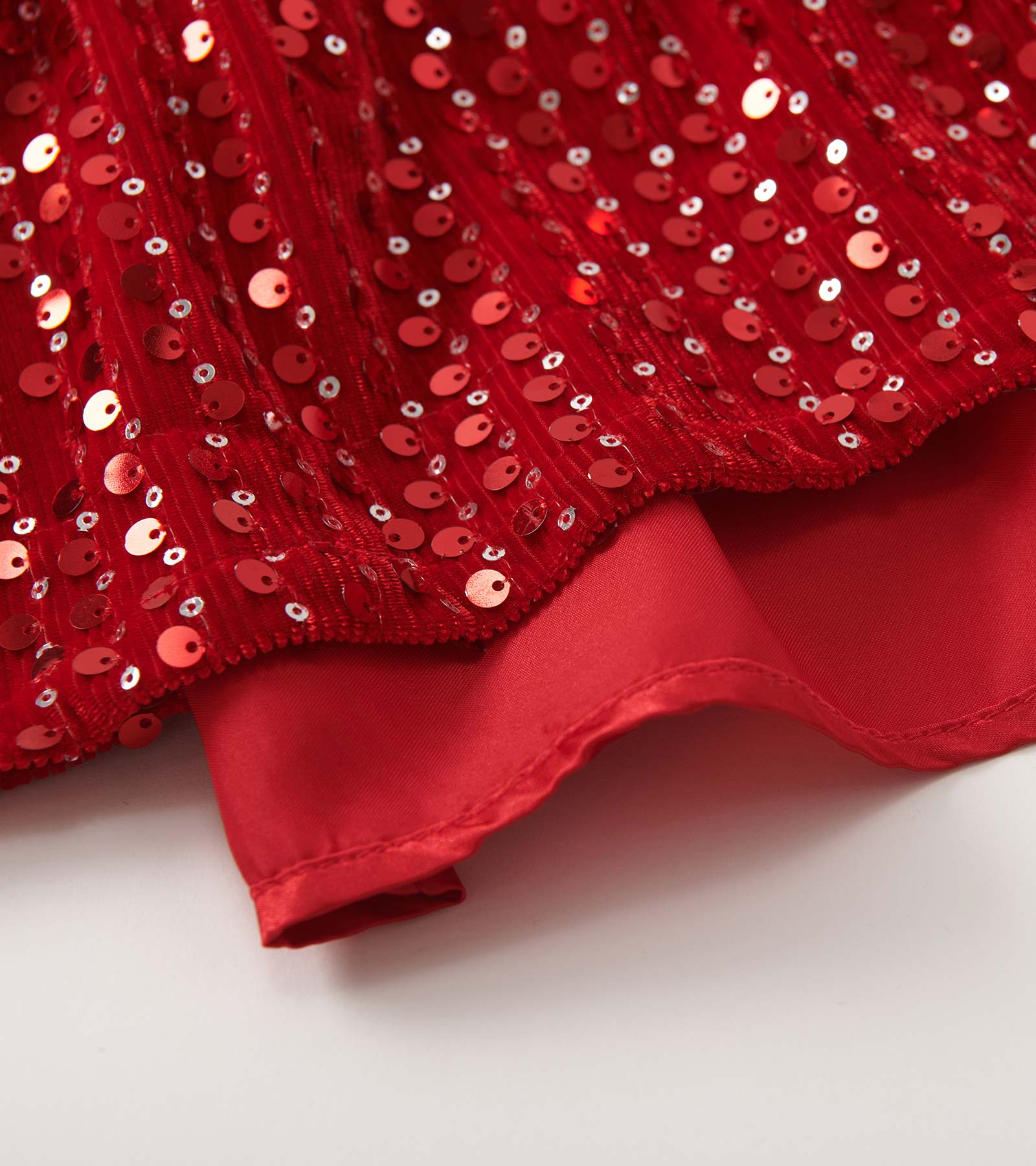 Red velvet dress adorned with sequins, featuring a smooth hem and a festive, sparkly design.