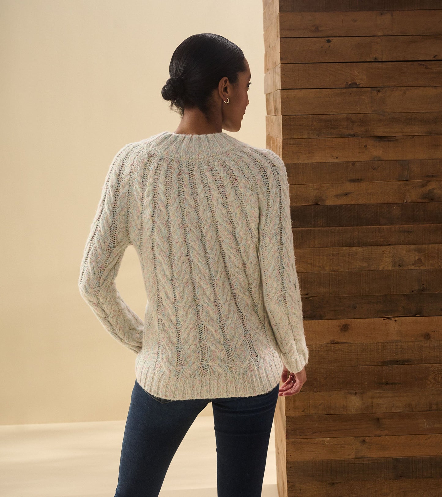 Cable knit sweater in clear rainbow colors, featuring a relaxed fit and ribbed hem, viewed from the back.
