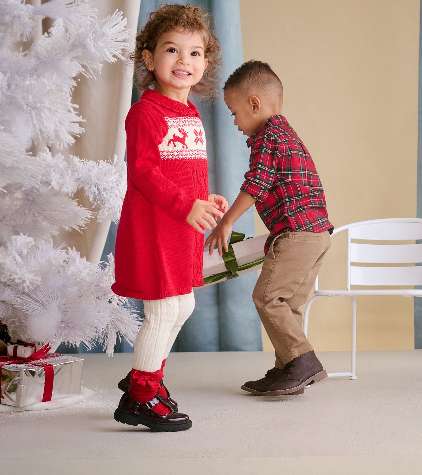 Red cable knit sweater dress with white holiday pattern, paired with cream tights and black shoes, worn by a smiling girl.