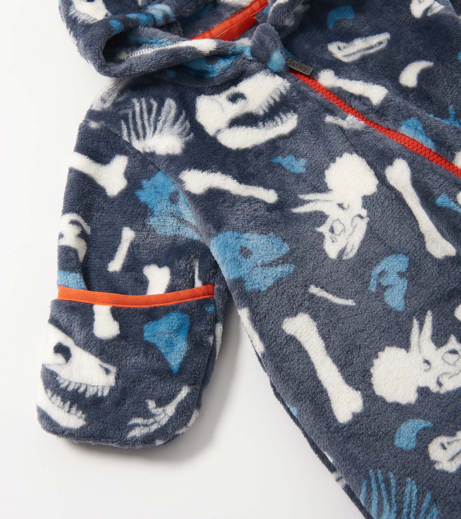 Navy fleece suit featuring dinosaur fossil patterns in white and blue, with an orange trim on the pocket and zipper.