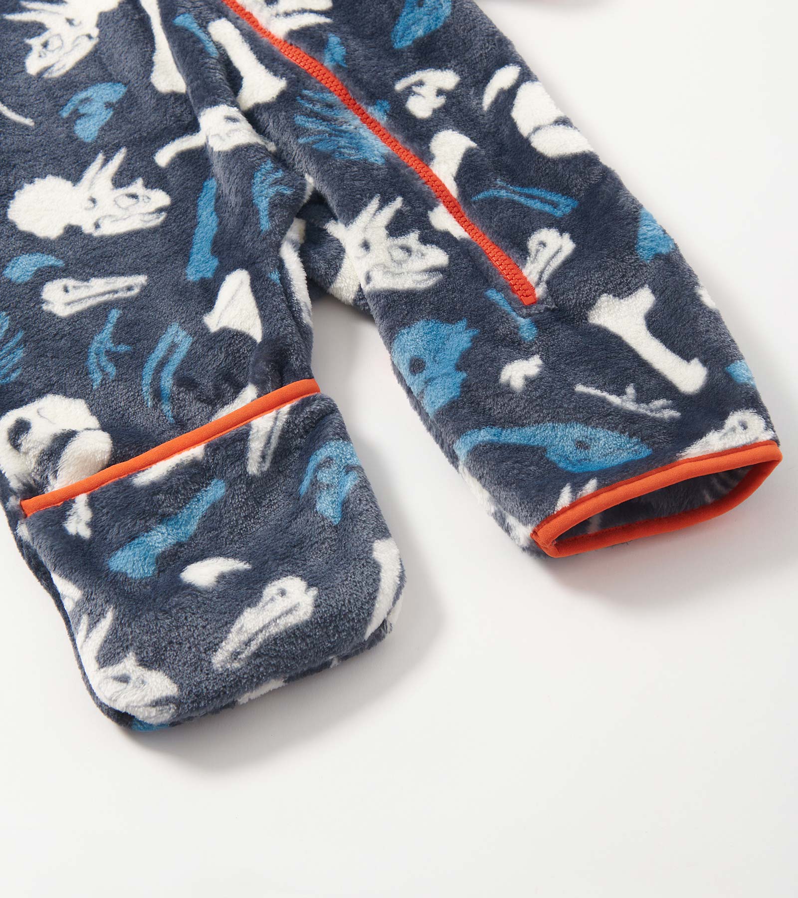 Navy fleece suit featuring white and blue dinosaur fossil patterns, with orange trim on the cuffs and zipper.