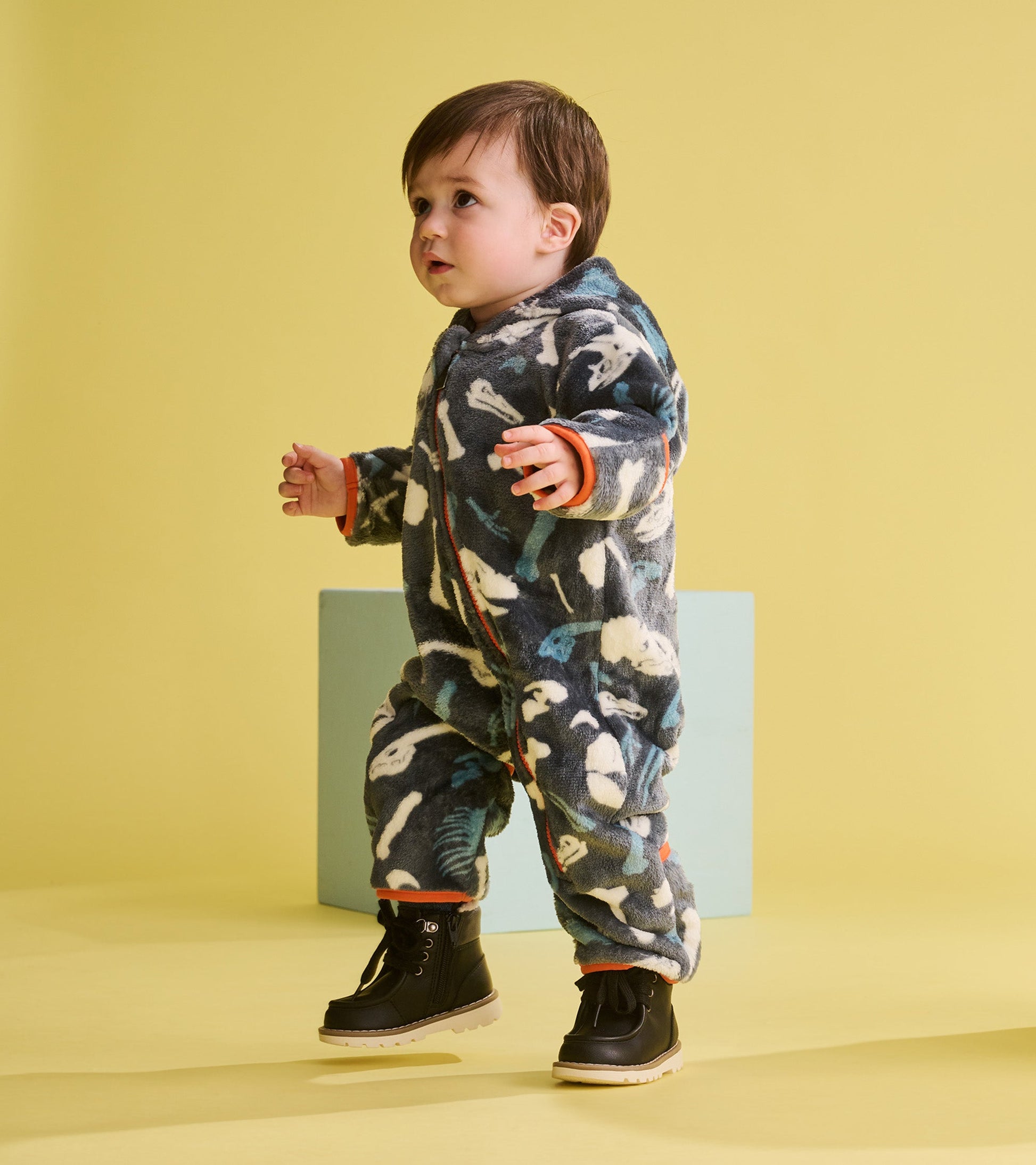Fleece suit for baby boys featuring a dinosaur fossil pattern, with orange accents and a cozy fit.