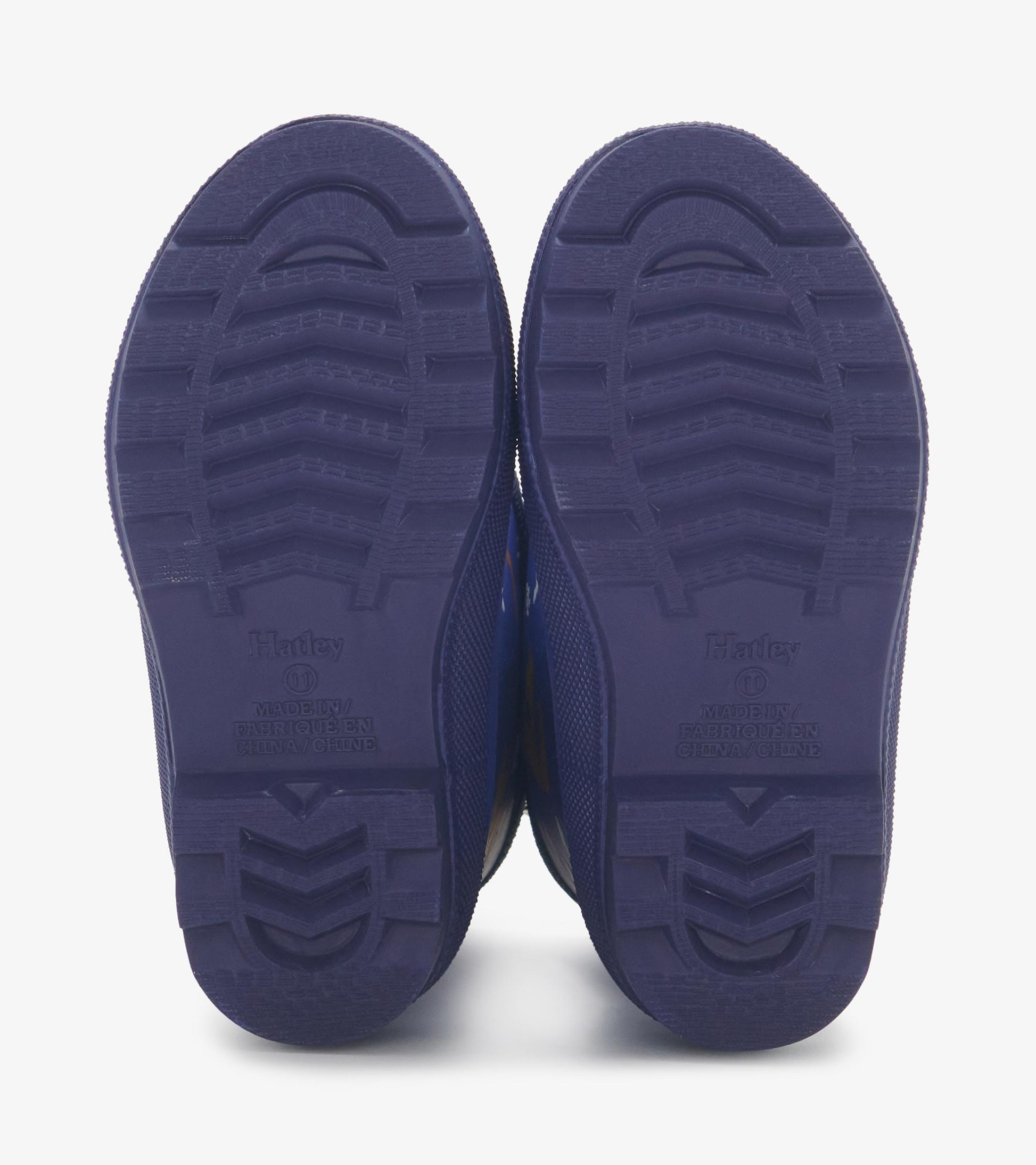 Matte blue rain boots with dinosaur fossil patterns, featuring textured purple soles for grip and stability.