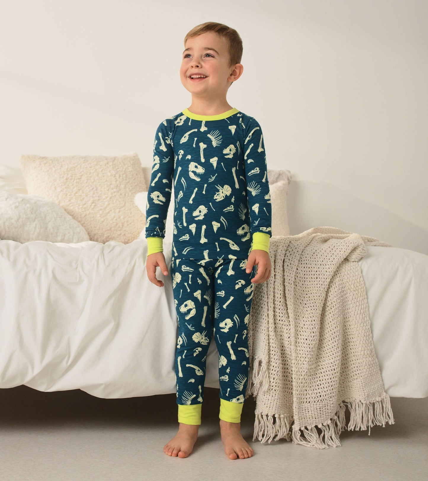 Navy pajama set featuring dinosaur fossil prints, with bright yellow cuffs, suitable for boys.