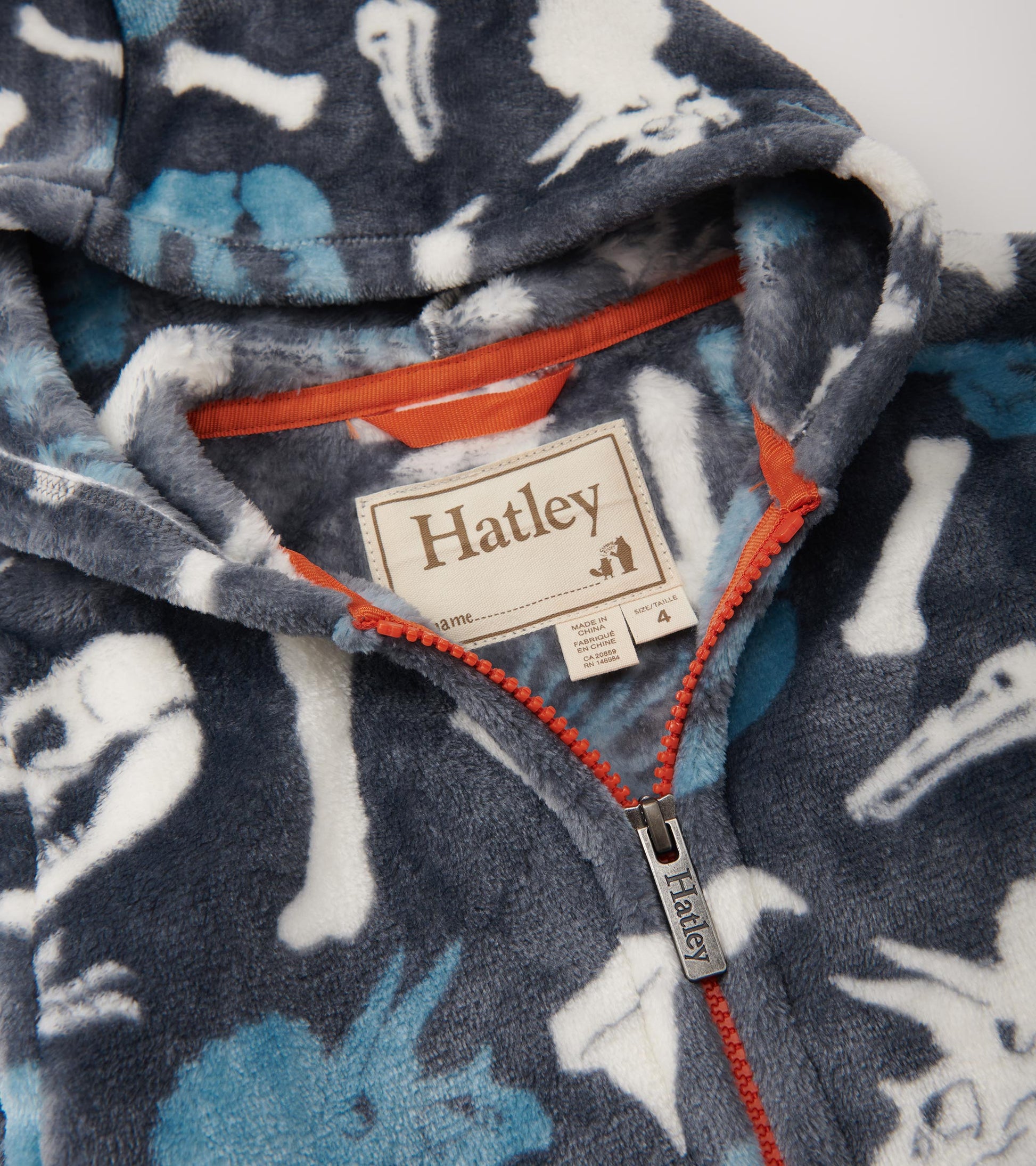 Fleece zip-up hoodie featuring a dinosaur fossil pattern in blue and white on a dark background, with an orange zipper.