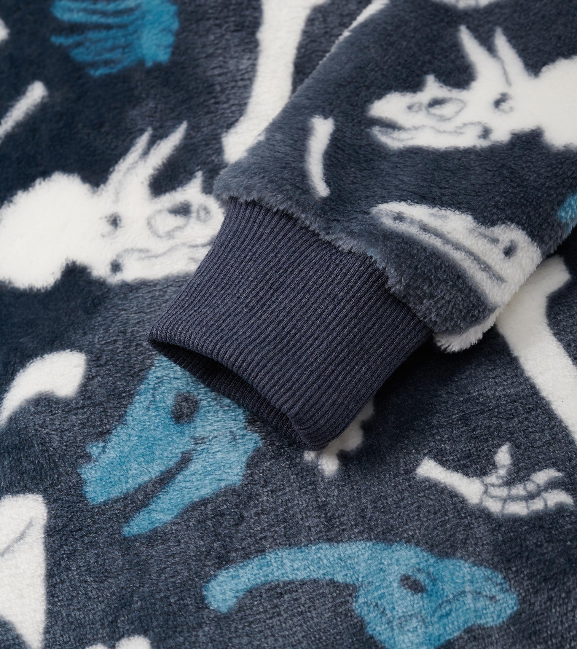 Navy fleece zip-up hoodie featuring dinosaur fossil patterns in white and blue, with ribbed cuffs for a snug fit.