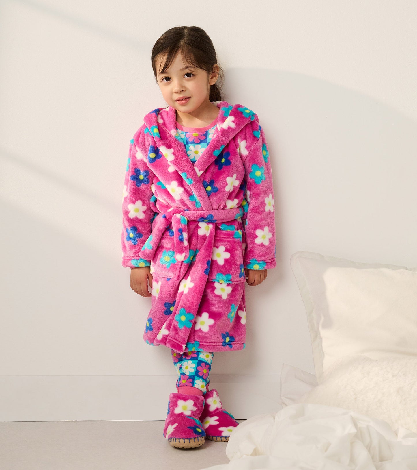 Pink fleece slippers with daisy pattern, featuring a soft, cozy design for baby girls.