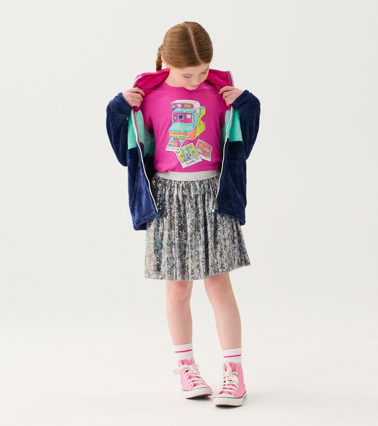 Shimmering sequin tulle skirt with a flared shape, paired with a colorful graphic tee and pink sneakers.