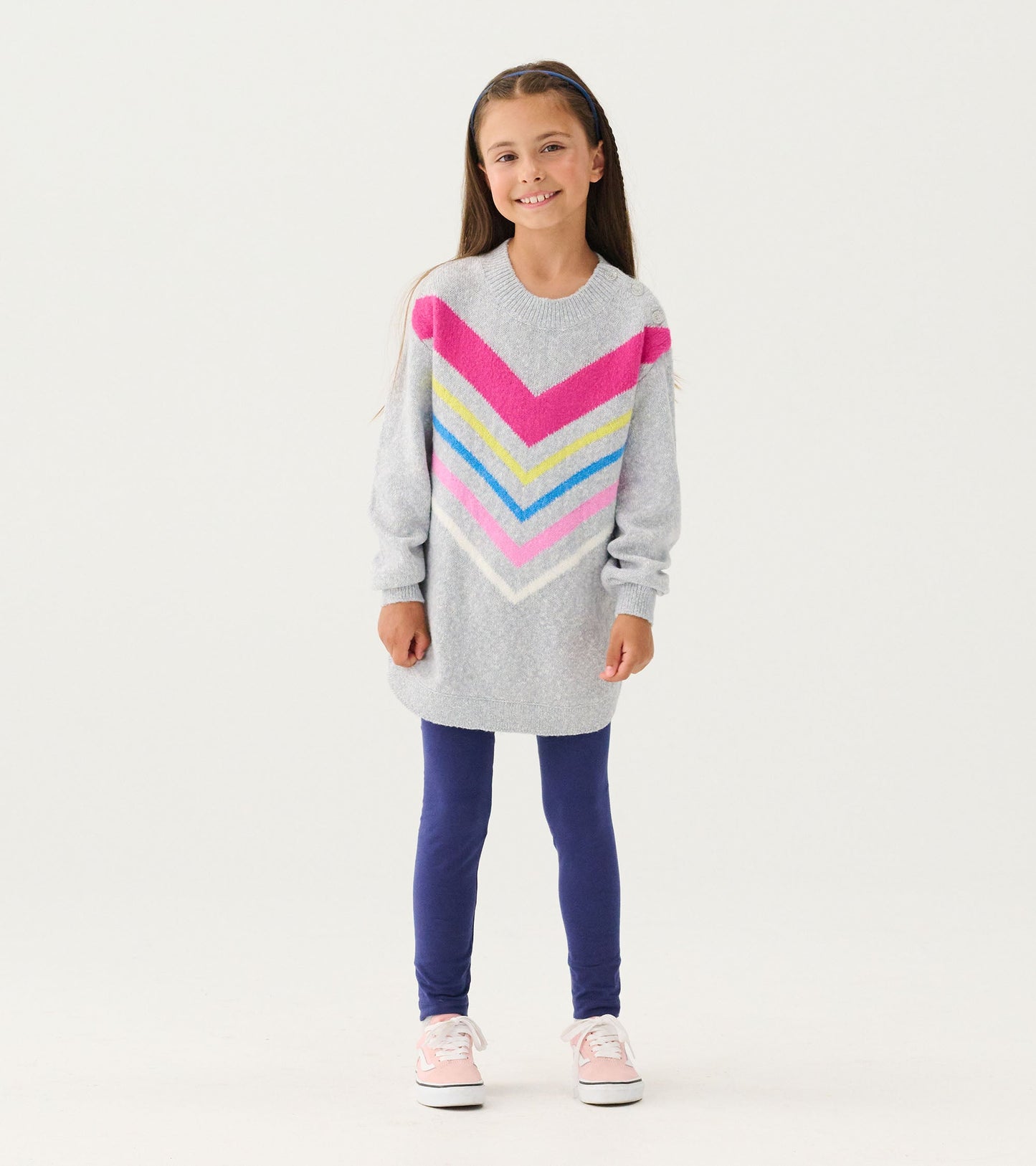 Gray chunky sweater tunic with chevron stripes in pink, blue, and yellow, paired with blue leggings and pink sneakers.
