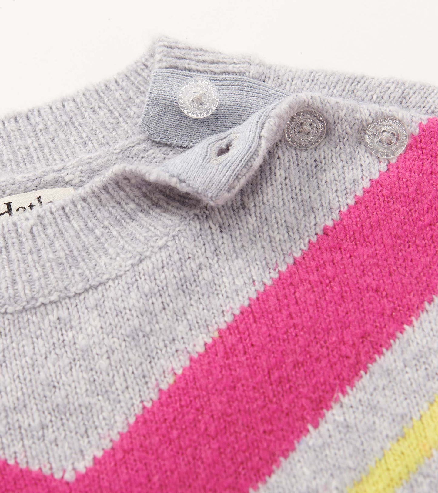 Gray chunky sweater tunic featuring chevron stripes in pink, yellow, and white, with button details at the neckline.