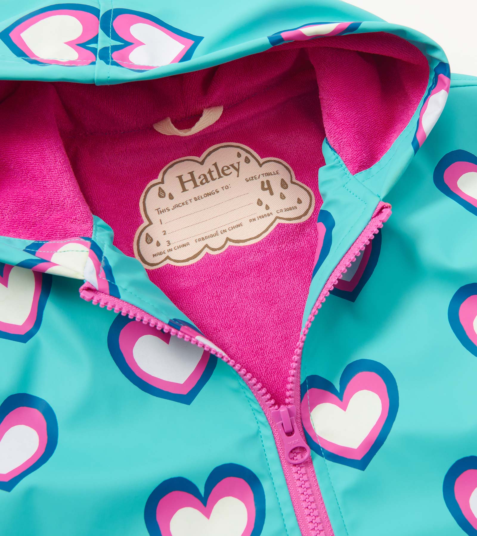Turquoise rain jacket with pink and white heart pattern, featuring a zip-up front and a soft pink interior lining.