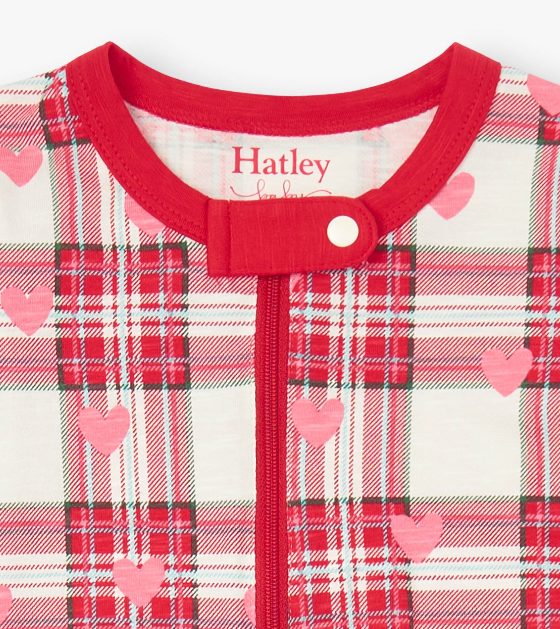 Red and white plaid footed sleeper with pink hearts, featuring a round neckline and snap closure.