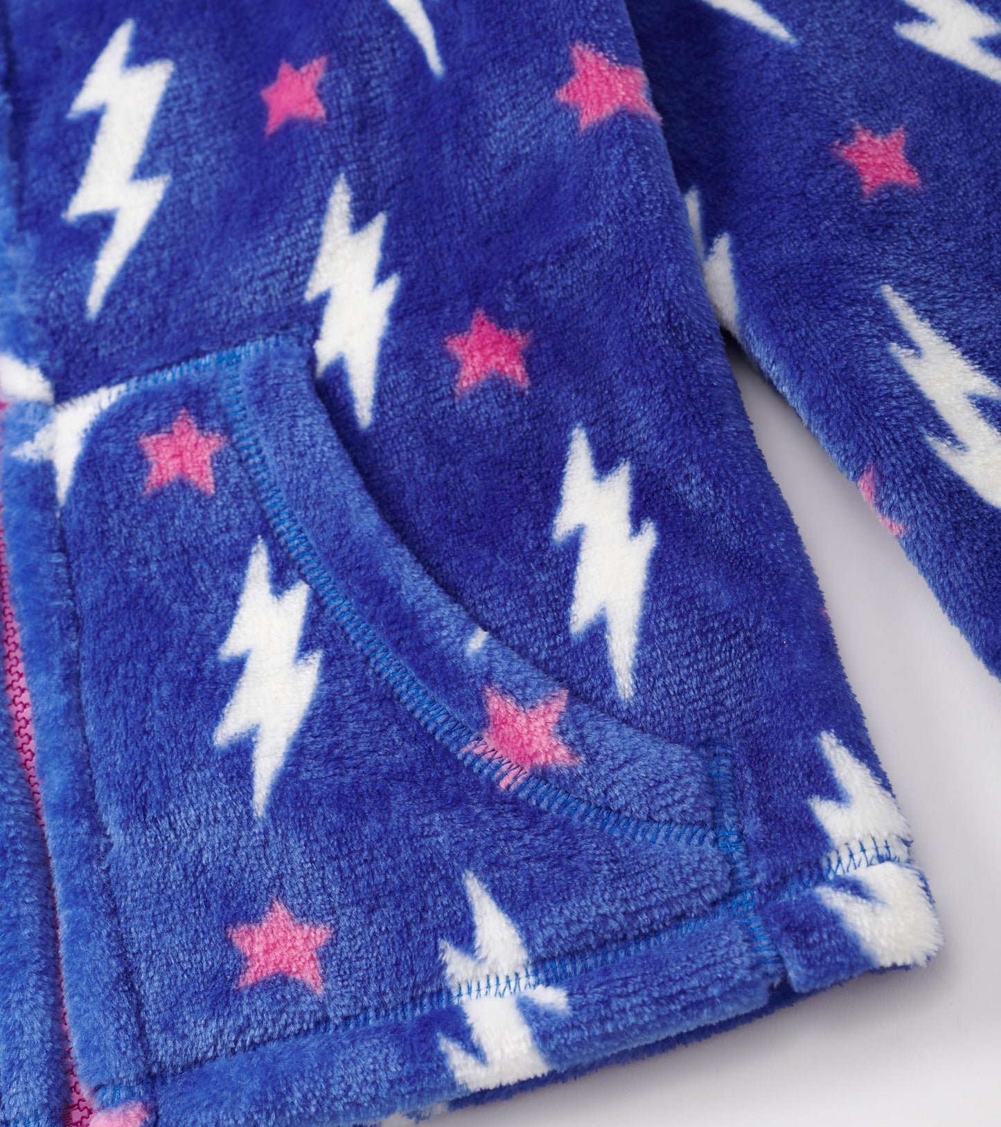 Fuzzy fleece zip-up jacket in blue with white lightning bolts and pink stars, featuring a front pocket.