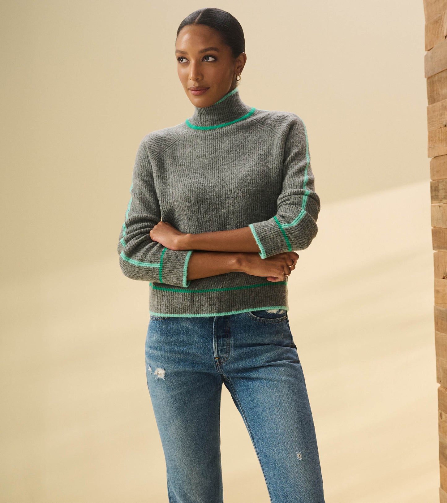 Charcoal heather pullover with a mock neck and contrasting teal stripes, styled with distressed blue jeans.