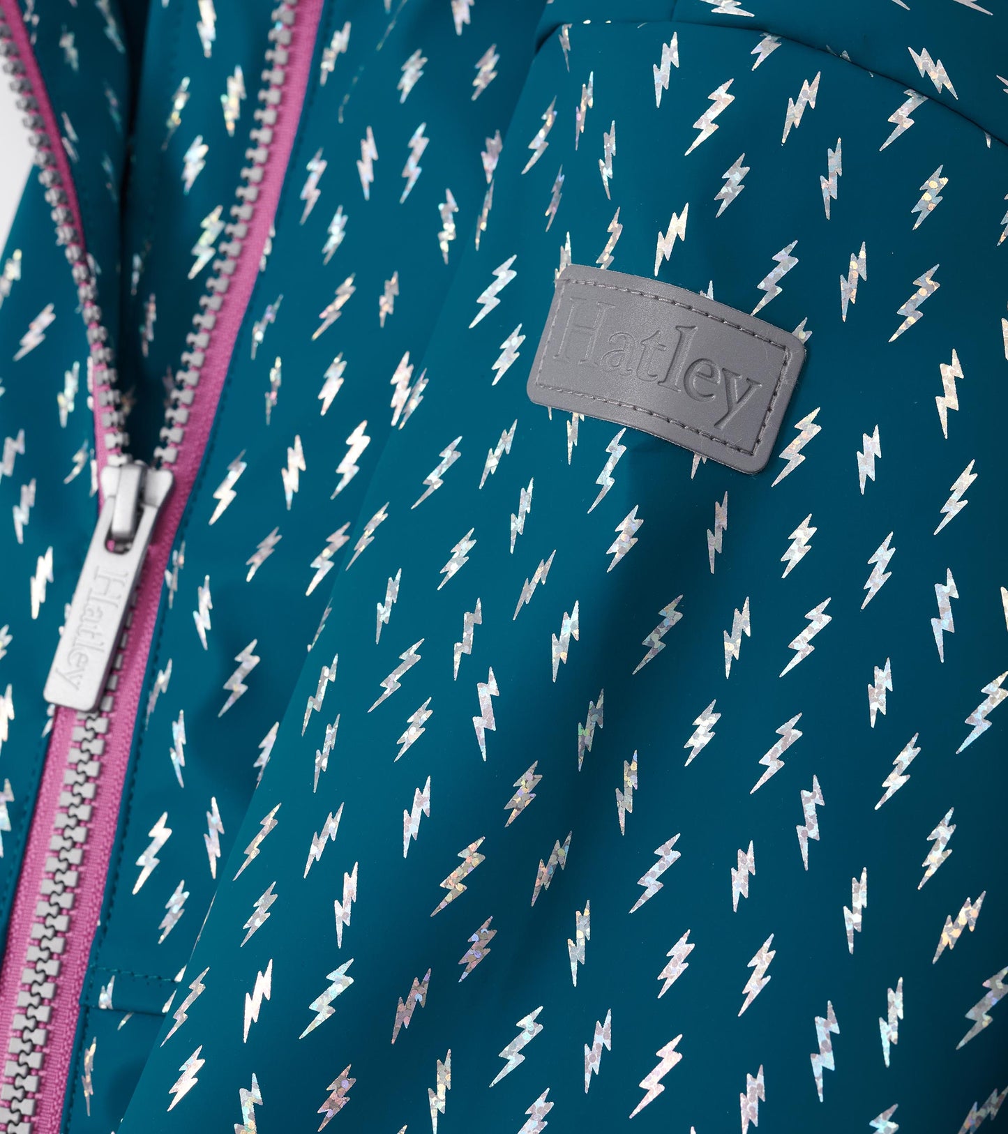 Teal rain jacket featuring metallic lightning bolt pattern and a pink zipper, ideal for rainy days.