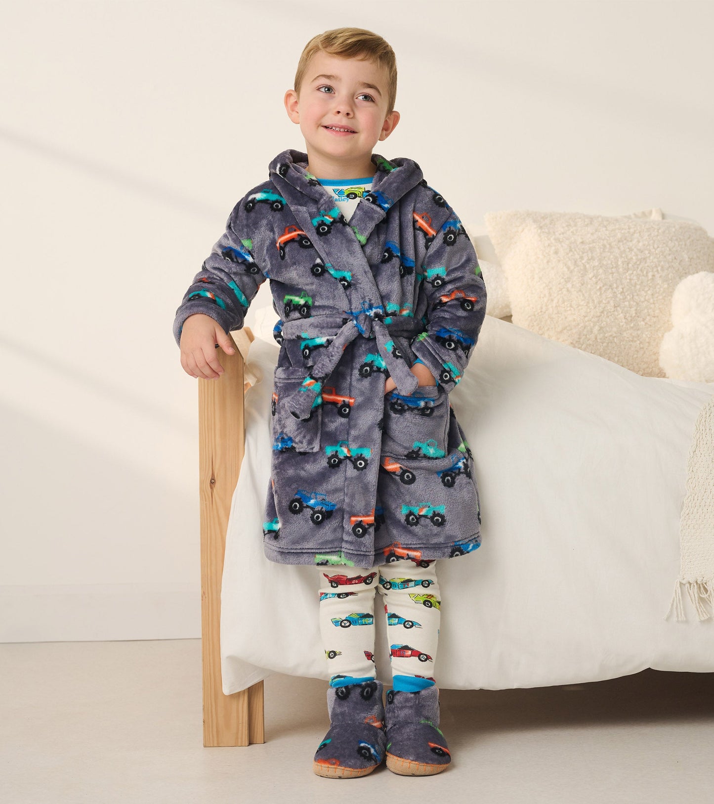 Gray fleece slippers featuring colorful monster truck designs, perfect for keeping little feet warm and cozy.