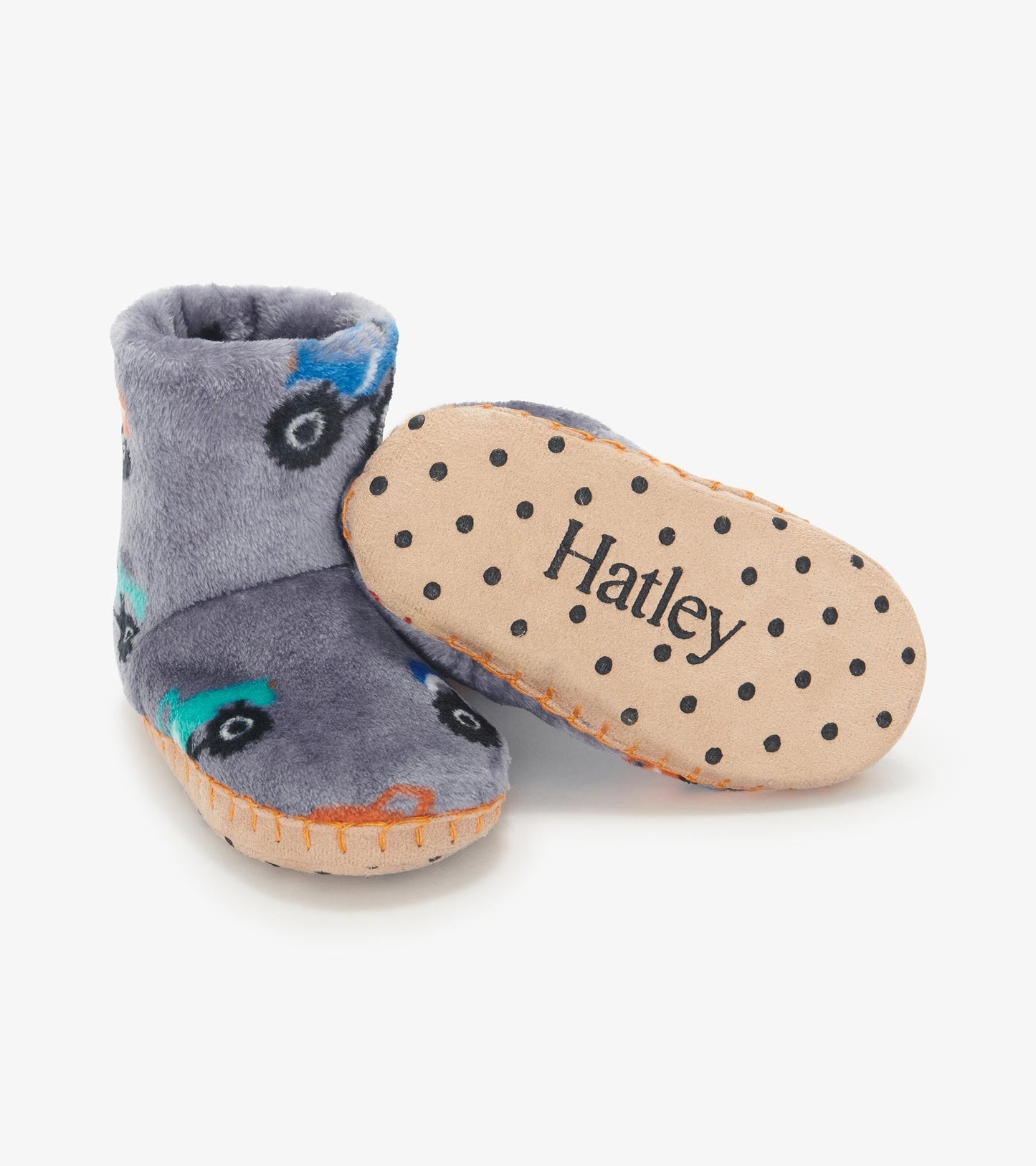 Gray fleece slippers featuring colorful monster truck designs and a soft, dotted sole for traction.