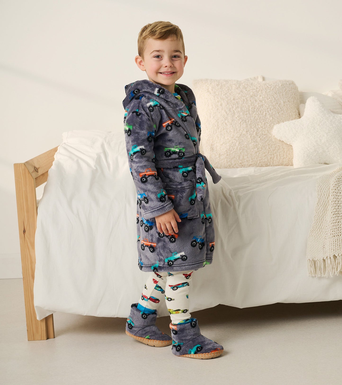 Gray fleece slippers with monster truck design, featuring a soft, cozy material and a slip-on style for toddlers.