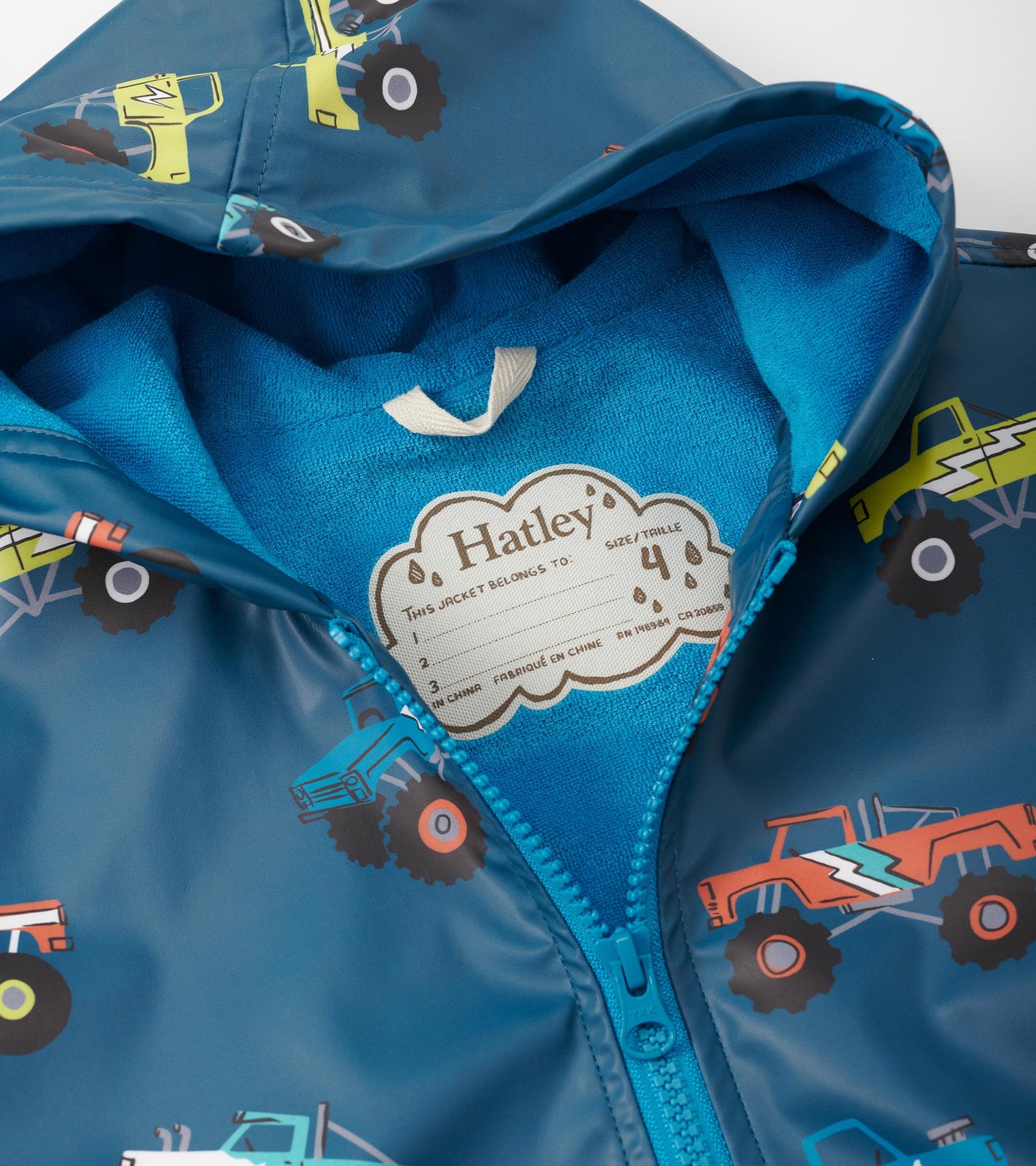 Blue zip-up rain jacket featuring colorful monster truck patterns and a soft inner lining. Size tag visible.