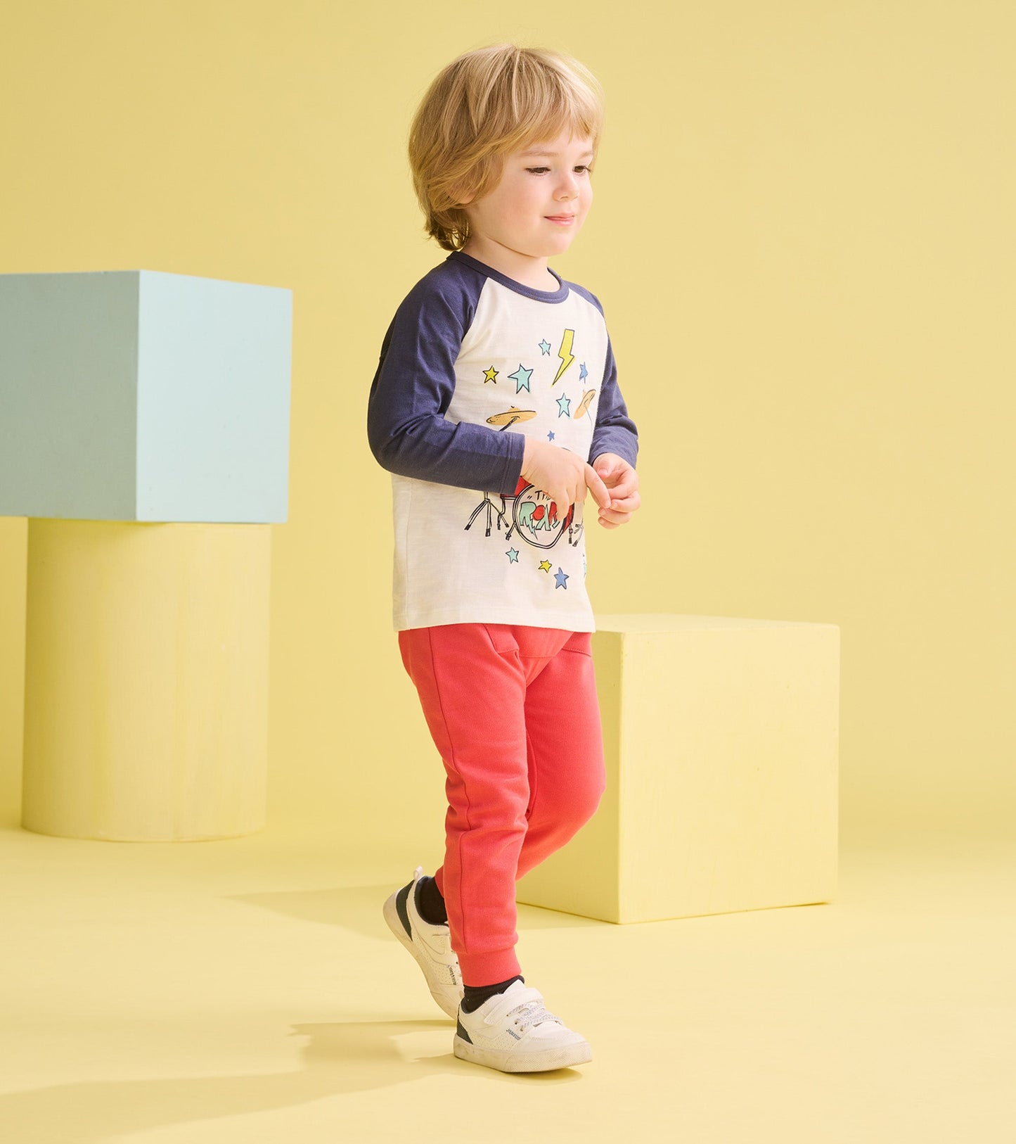 Long sleeve white t-shirt with navy sleeves, featuring a drum kit graphic and colorful stars, paired with pink pants.